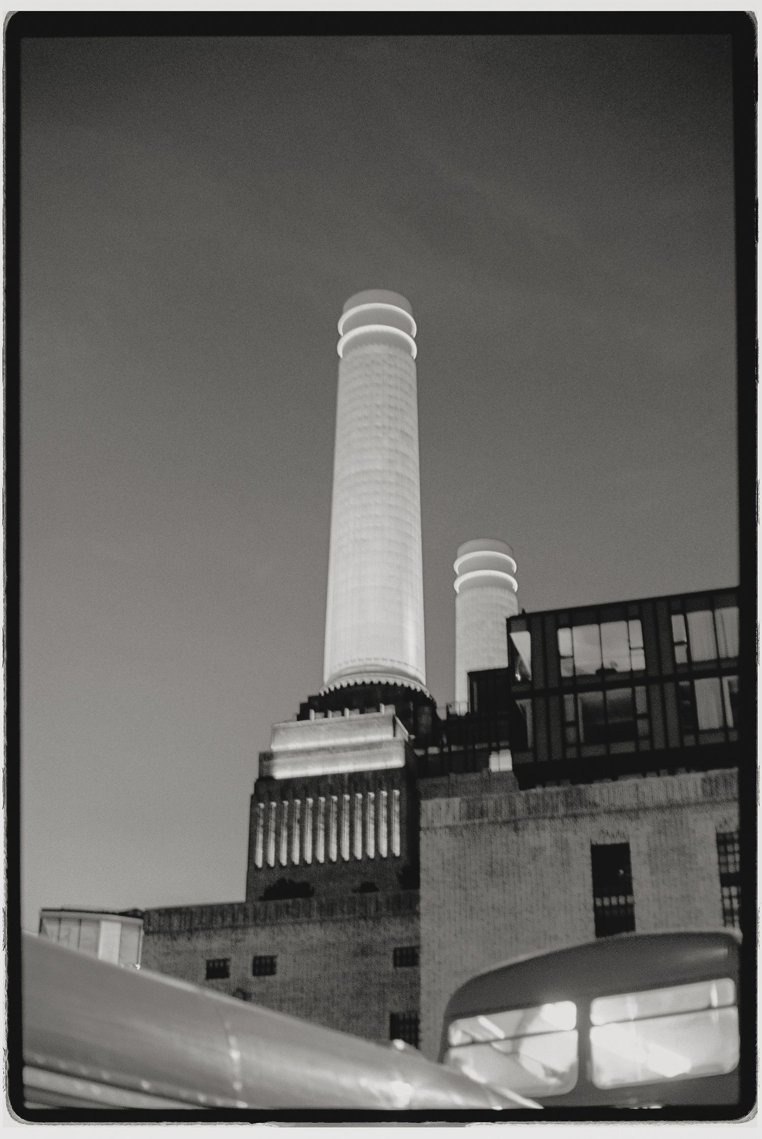 Black and white photograph of two tall industrial chimneys against a stark sky.