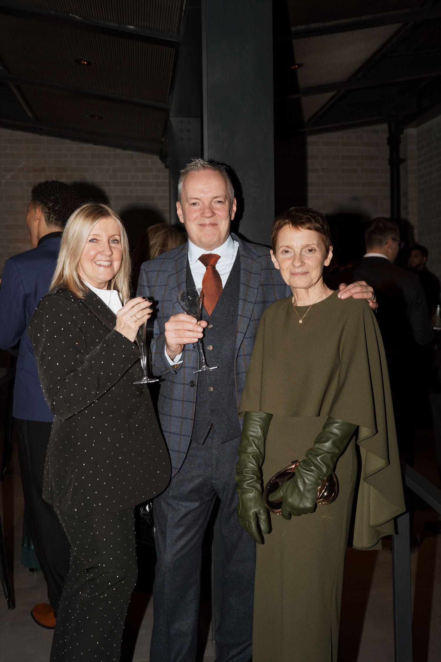 Group of guests in formal wear socializing at an evening party.