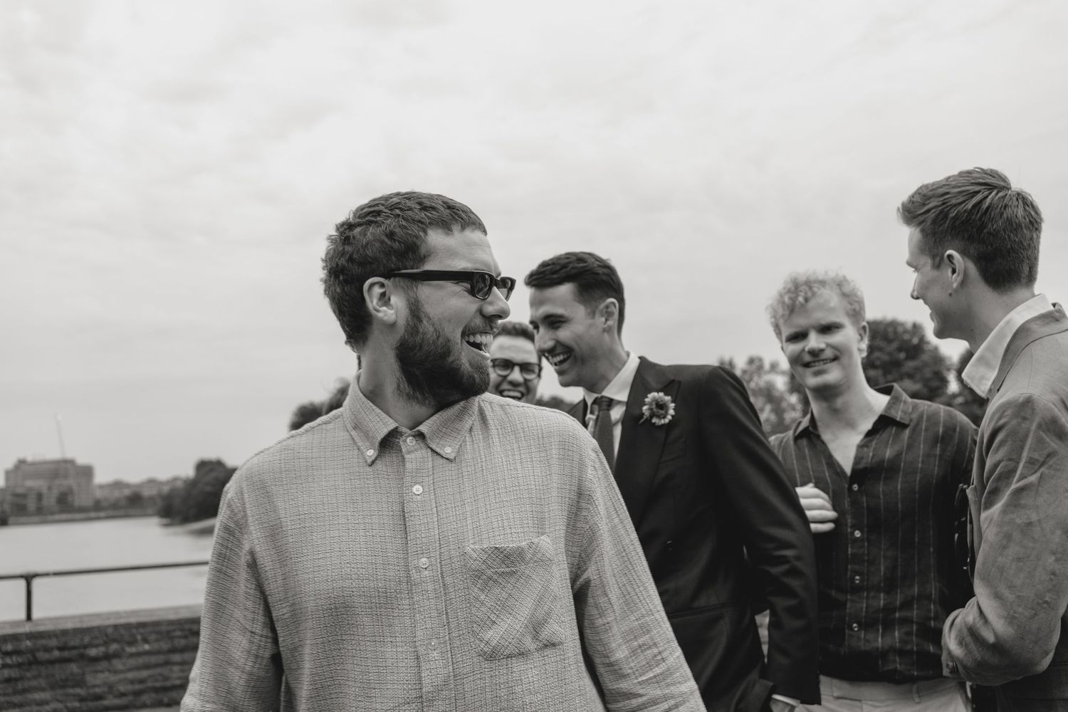 Wedding guests mingle and chat during an outdoor reception by the water.