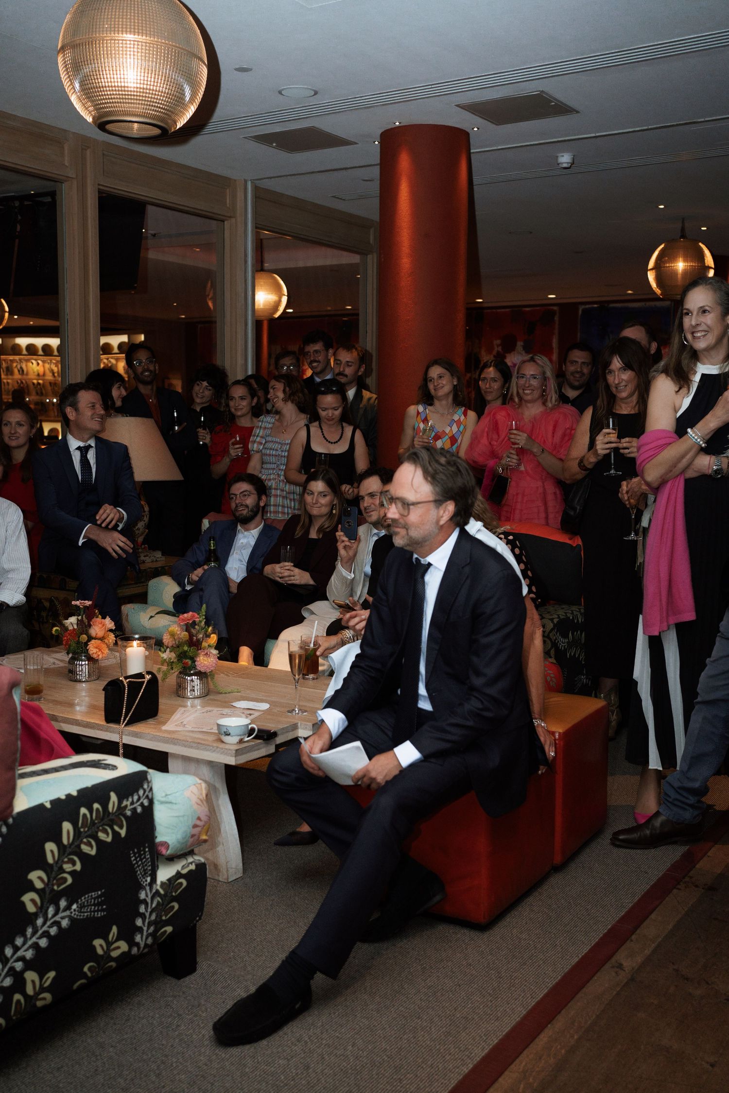 Wedding reception venue with guests seated and watching a presentation.