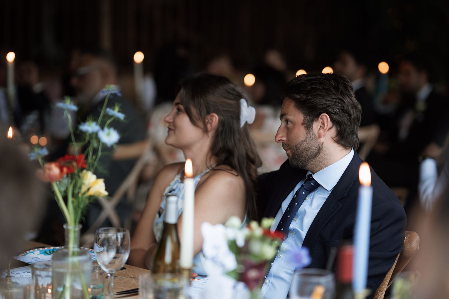 Candlelit wedding reception dinner with guests seated at elegantly decorated tables.