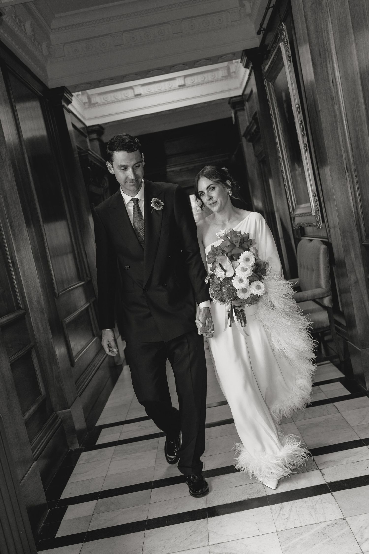 Couple walking down a marble hallway during their wedding celebration.