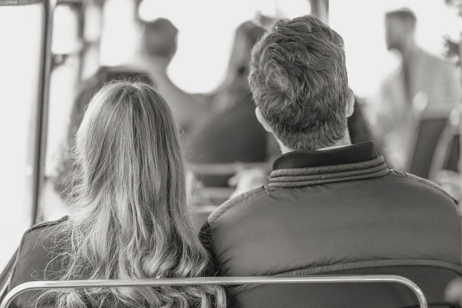 A couple sitting together on a bench in silhouette.