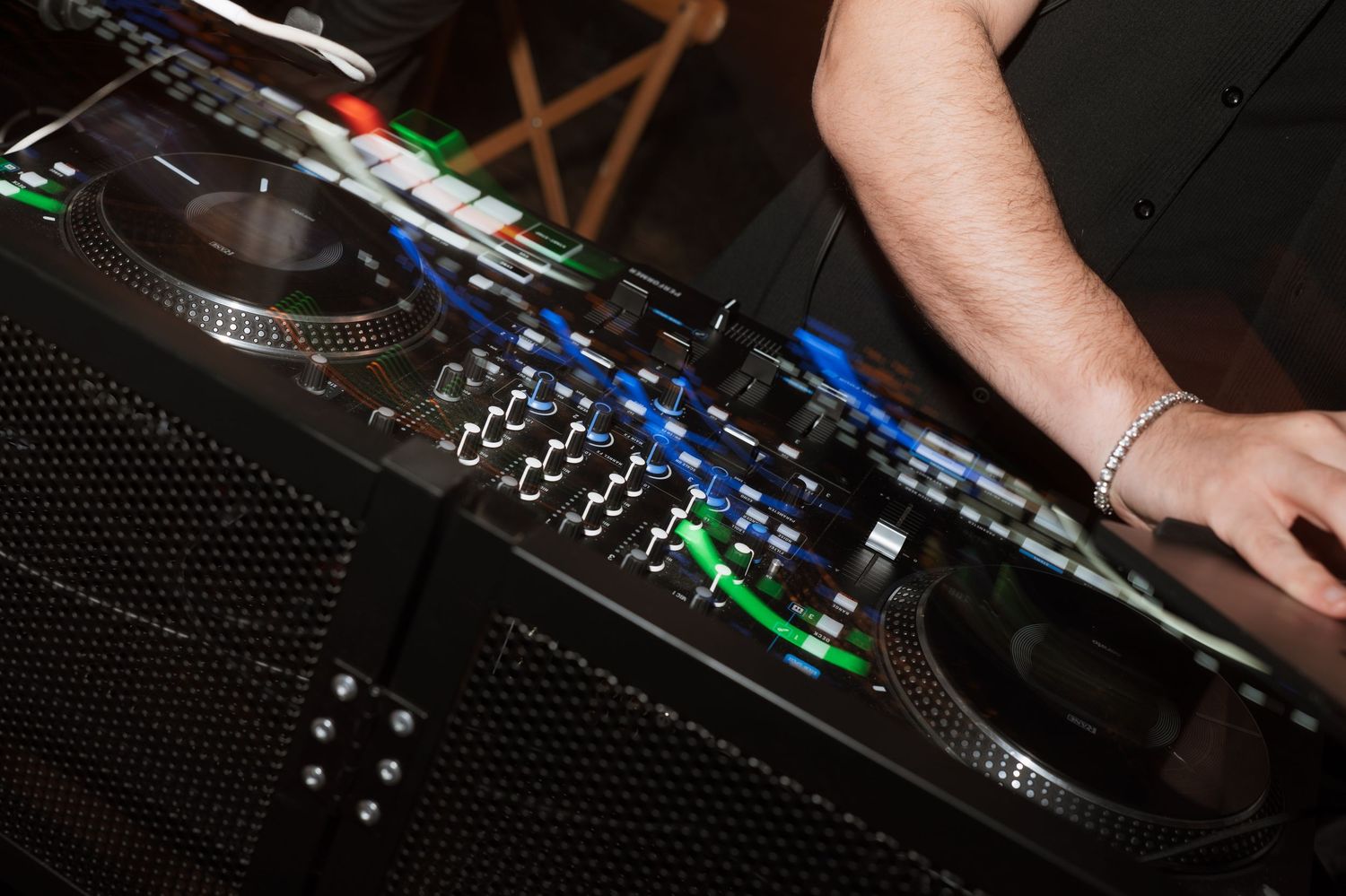 Close-up of DJ equipment with illuminated controls at a wedding reception.