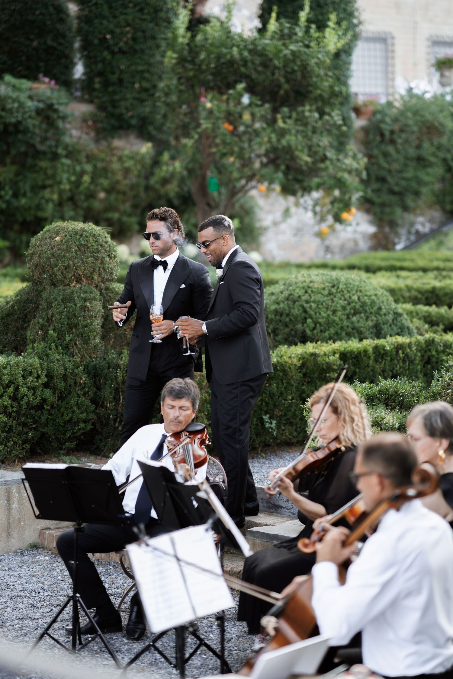 String quartet performs at outdoor wedding reception while guests mingle in background.