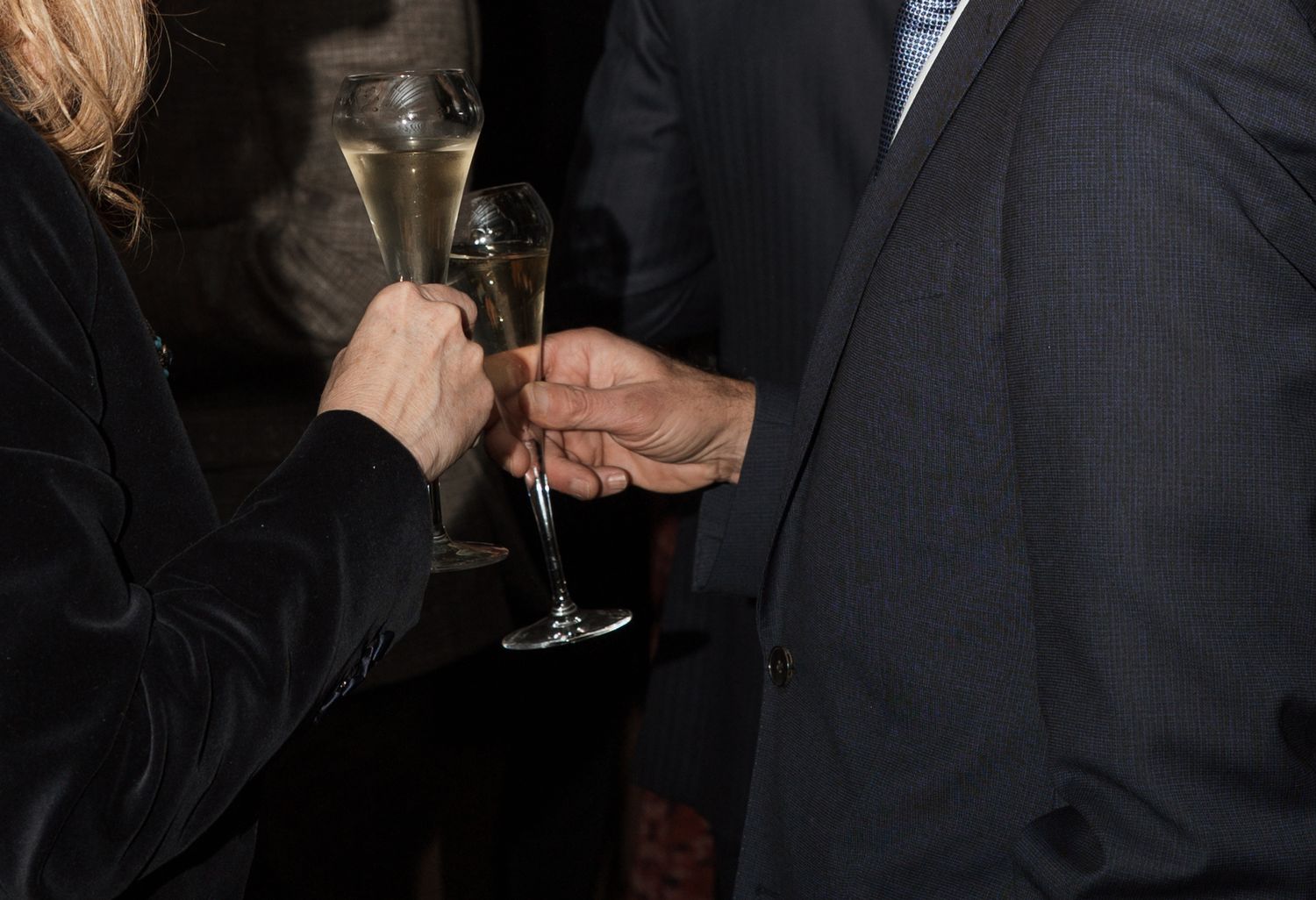 Guests mingling and holding drinks at a dimly lit social gathering.