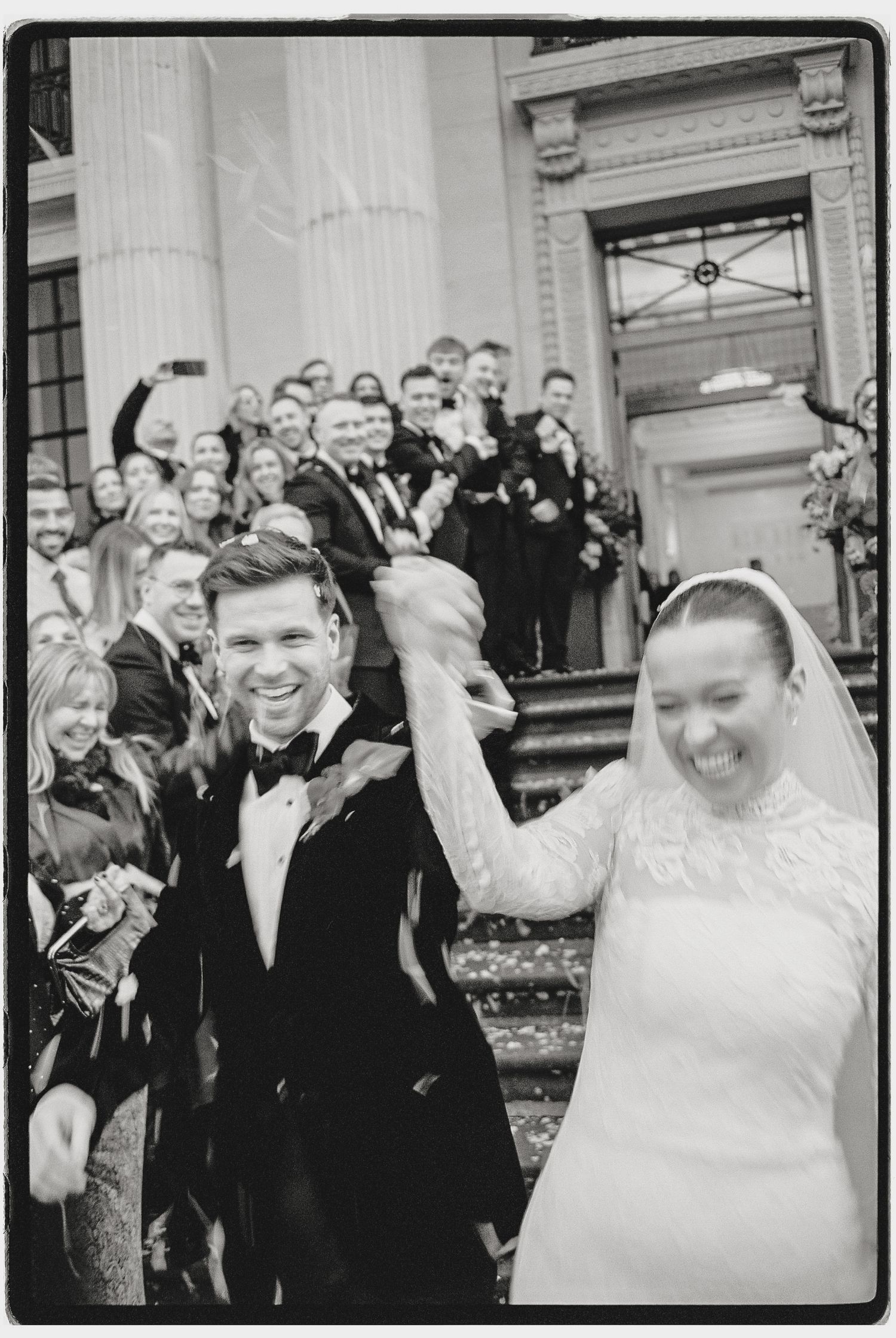 Joyful celebration captured in vintage black and white style outside historic building.