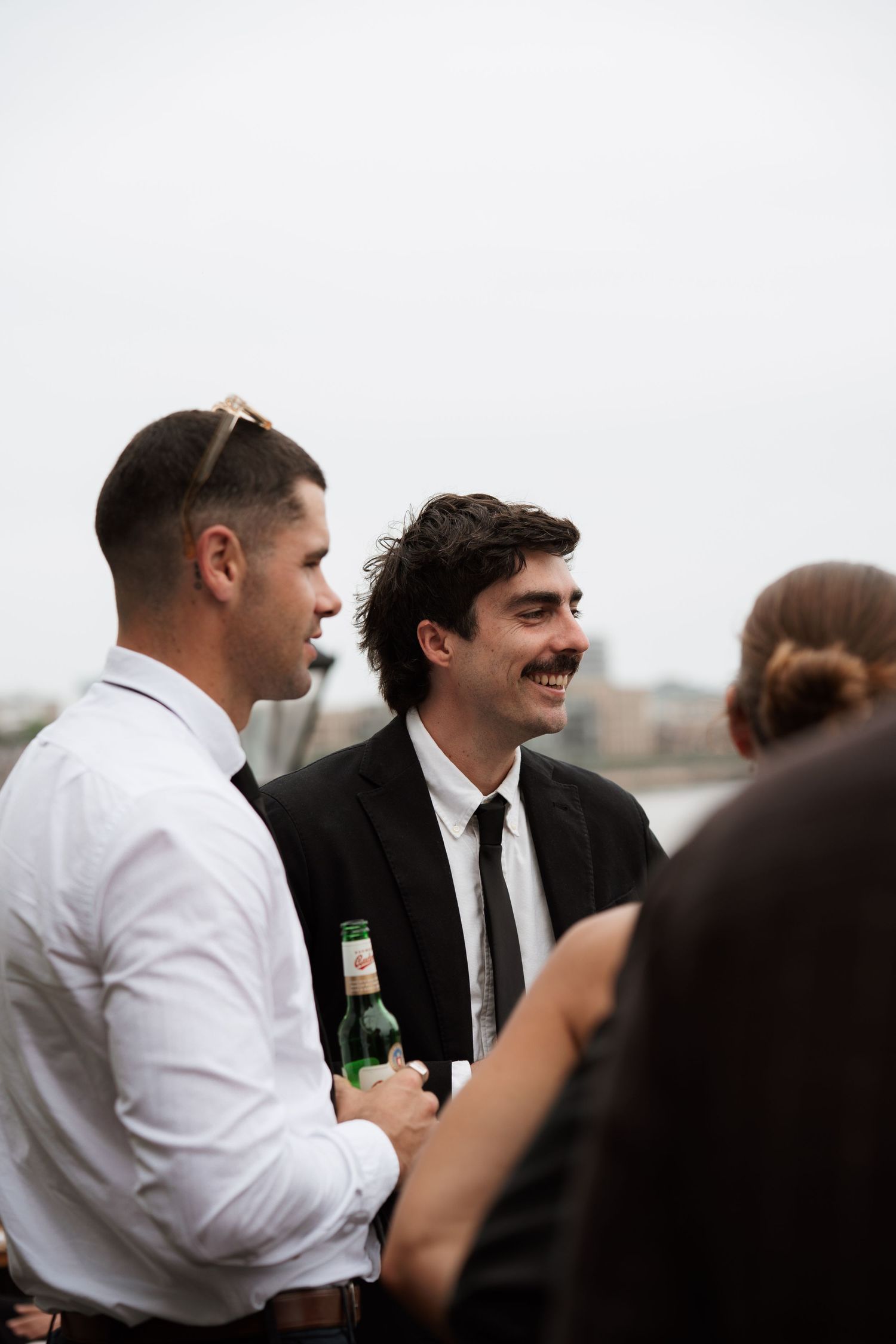 Wedding guests share laughs and drinks during an outdoor reception.