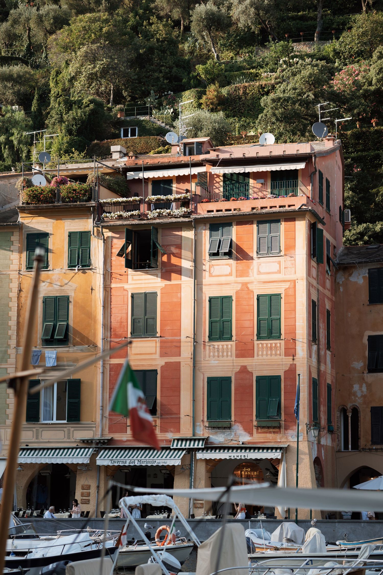 Pastel-colored waterfront buildings with boats moored along Italian coastal harbor.