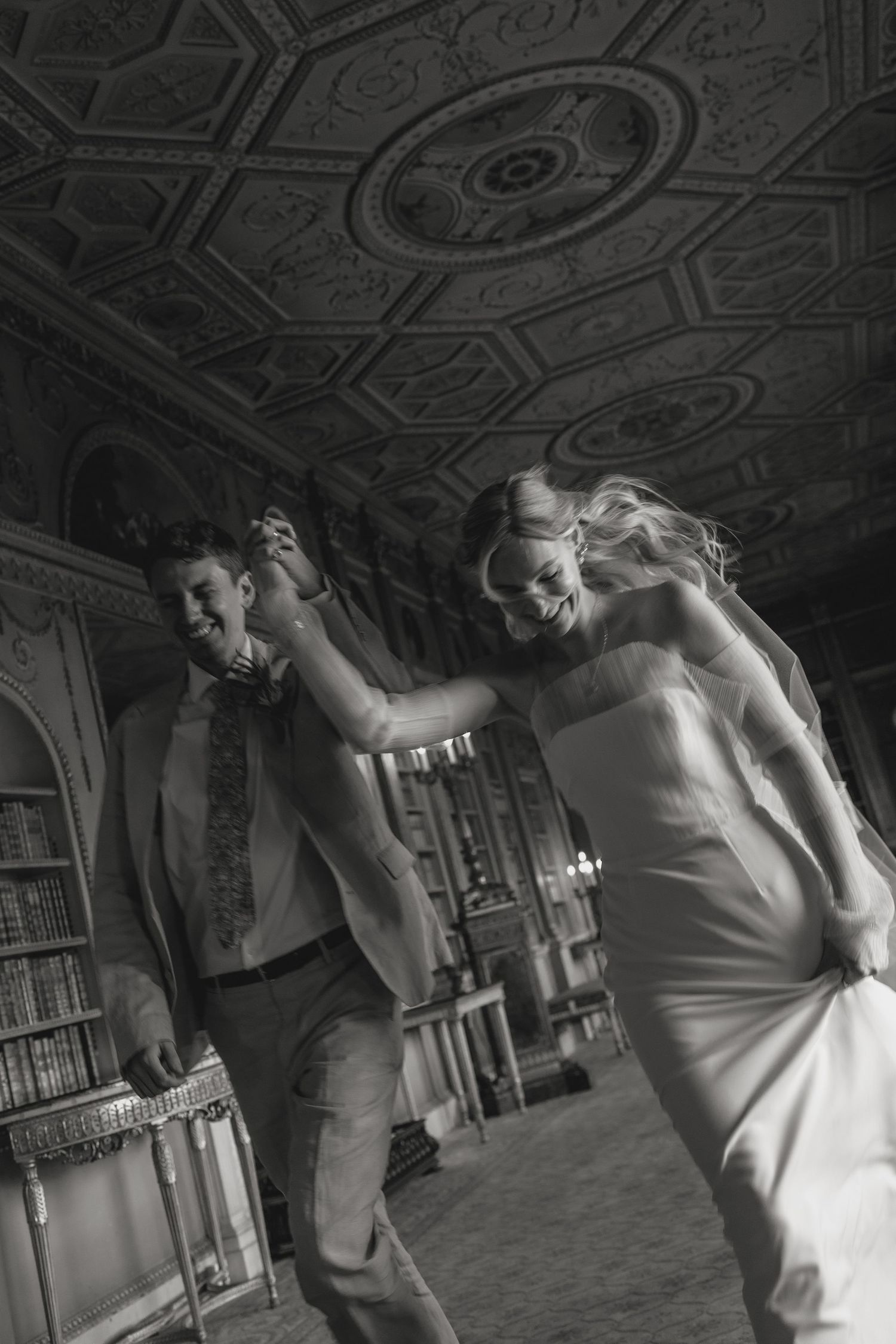 Wedding couple dancing in an elegant room with ornate ceiling details.
