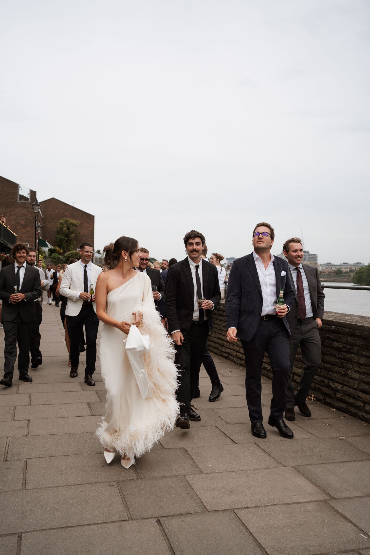 Wedding party walks along stone pathway during outdoor celebration.