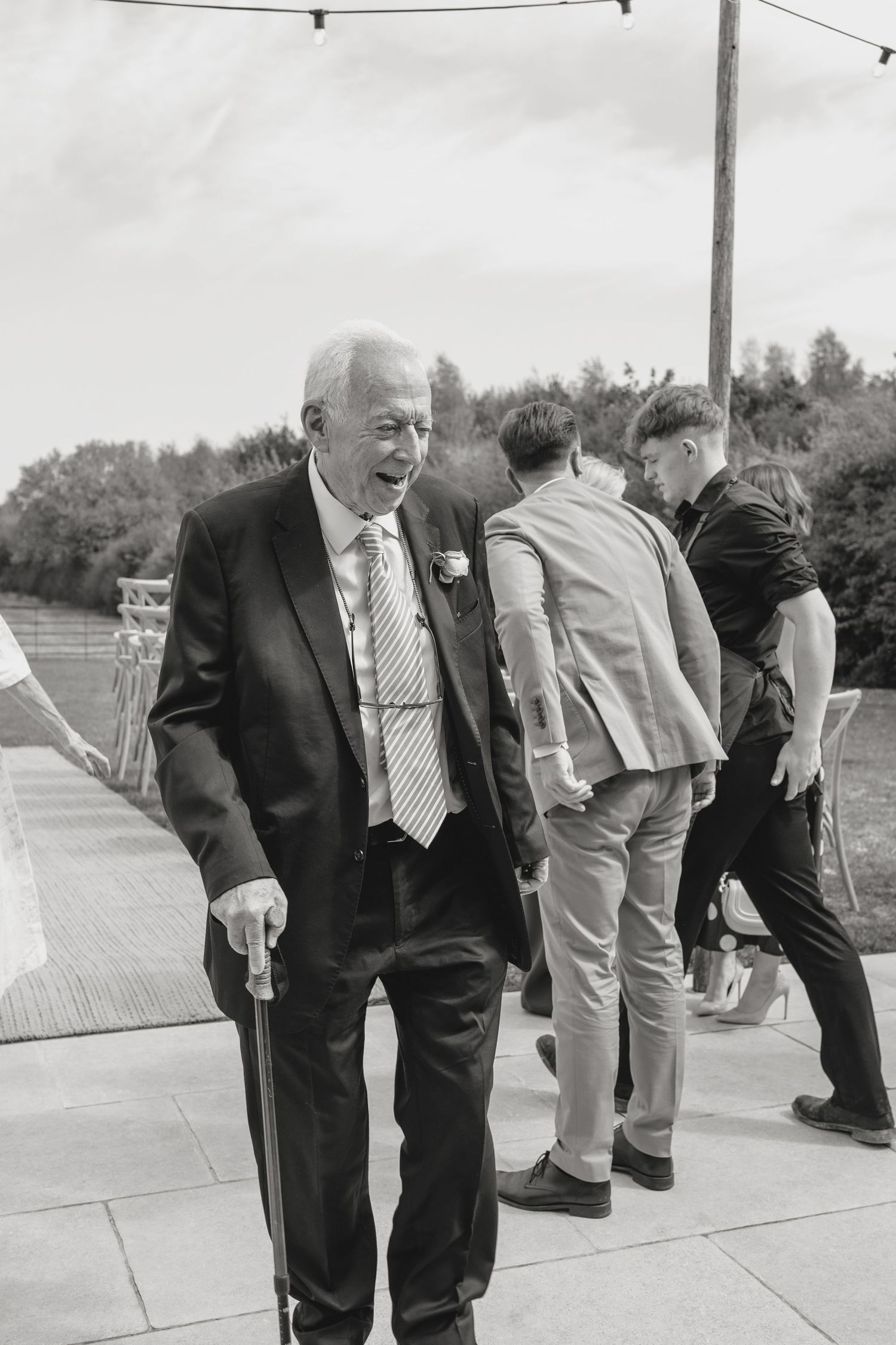 A group of formally dressed guests gather on a walkway during an outdoor event.