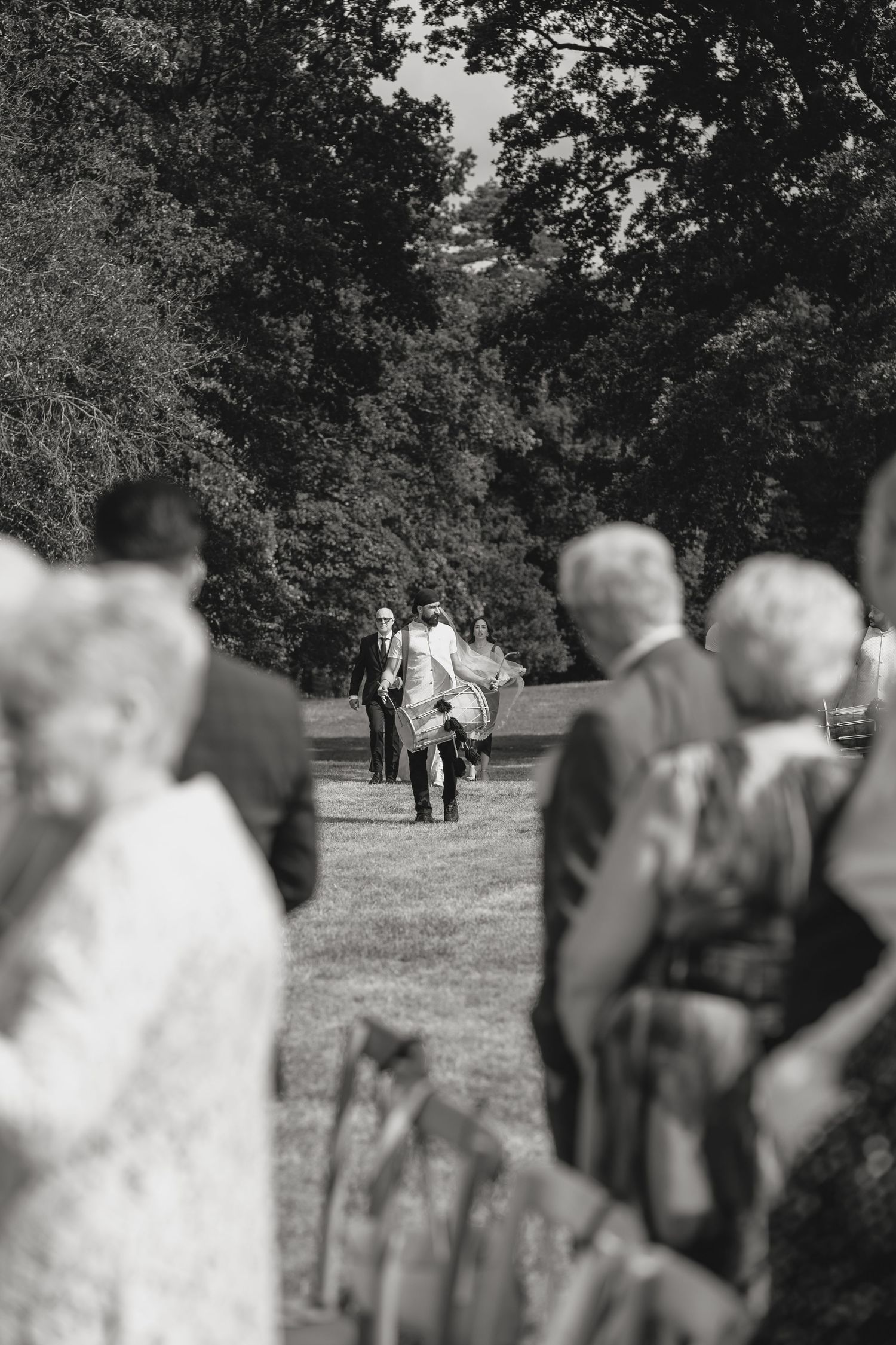 Blurred wedding guests gathered on a grassy lawn during an outdoor celebration.