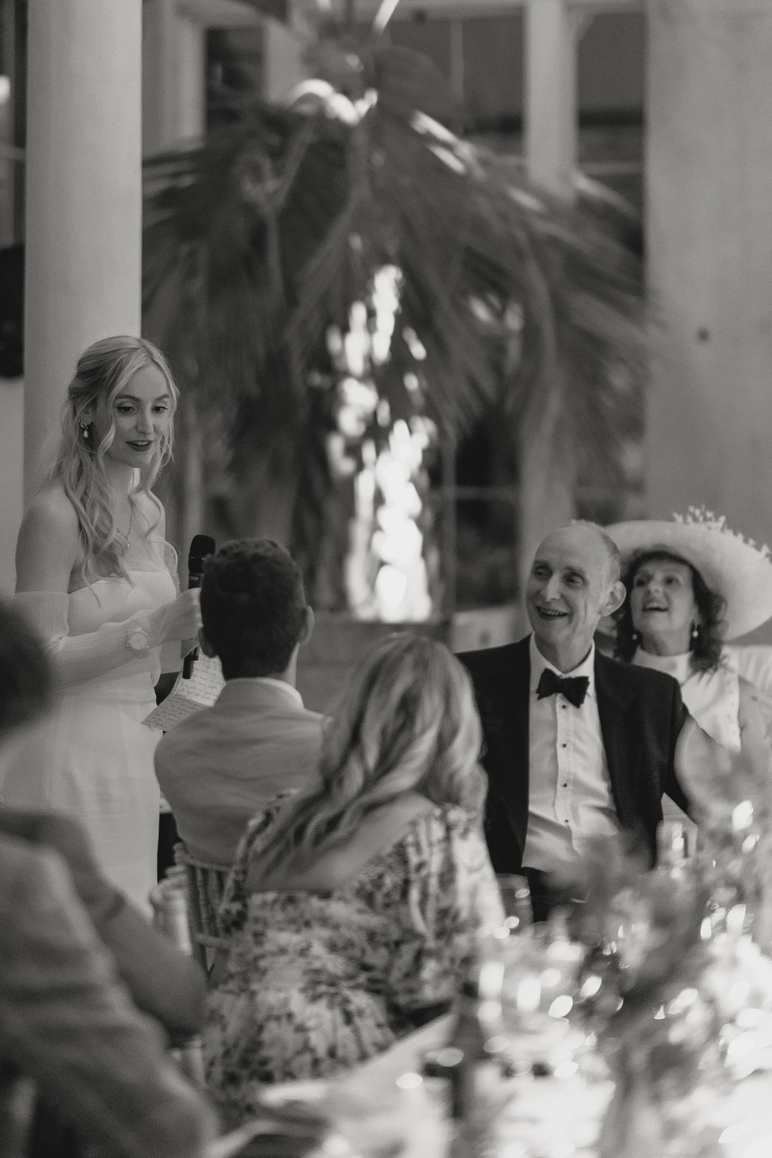 Wedding reception guests laughing and socializing during dinner in a columned venue.