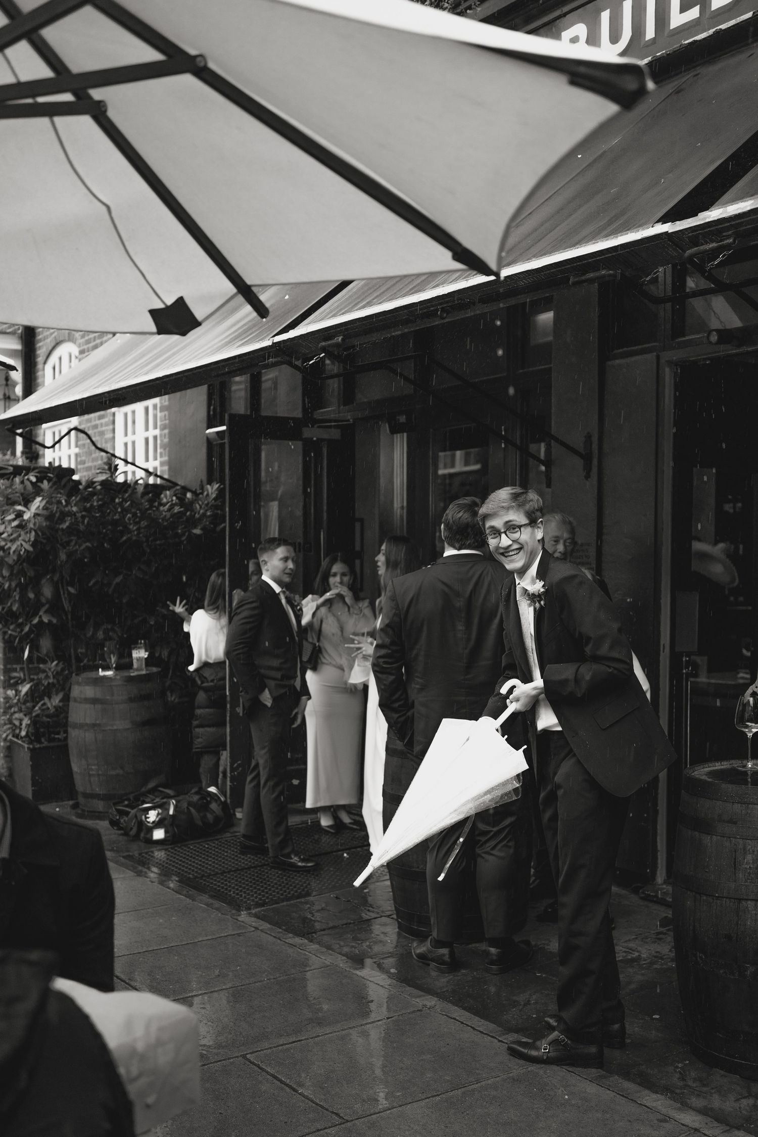 Black and white photo of people under storefront awnings.