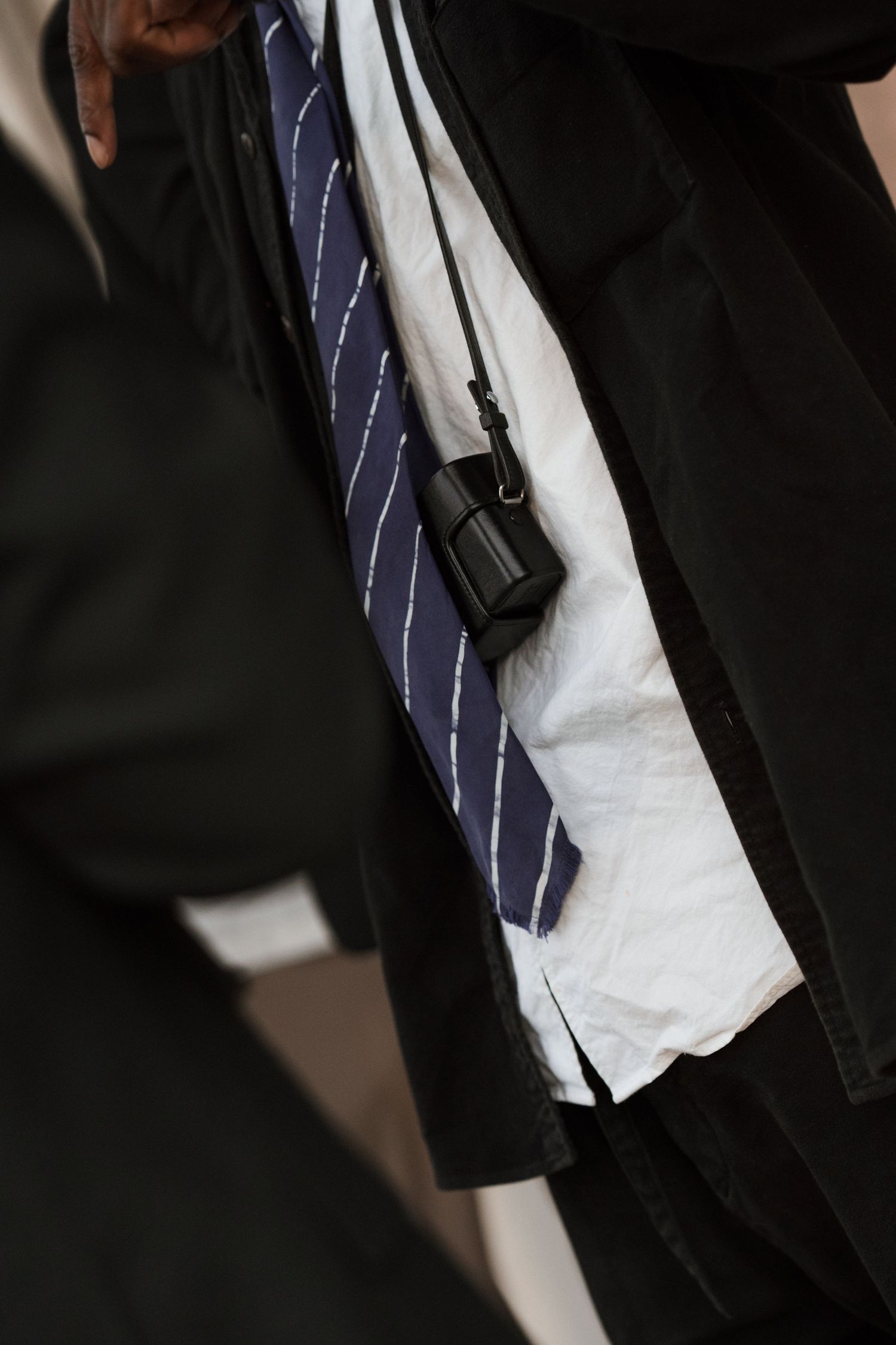 Close-up detail of a formal suit with striped tie against dark background.