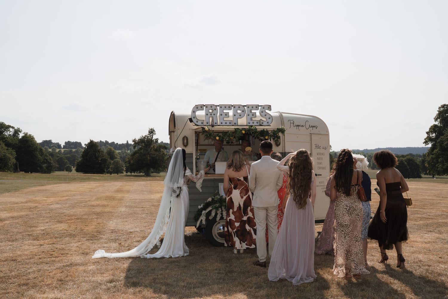 Wedding reception setup with white tents and decorations in an open field.