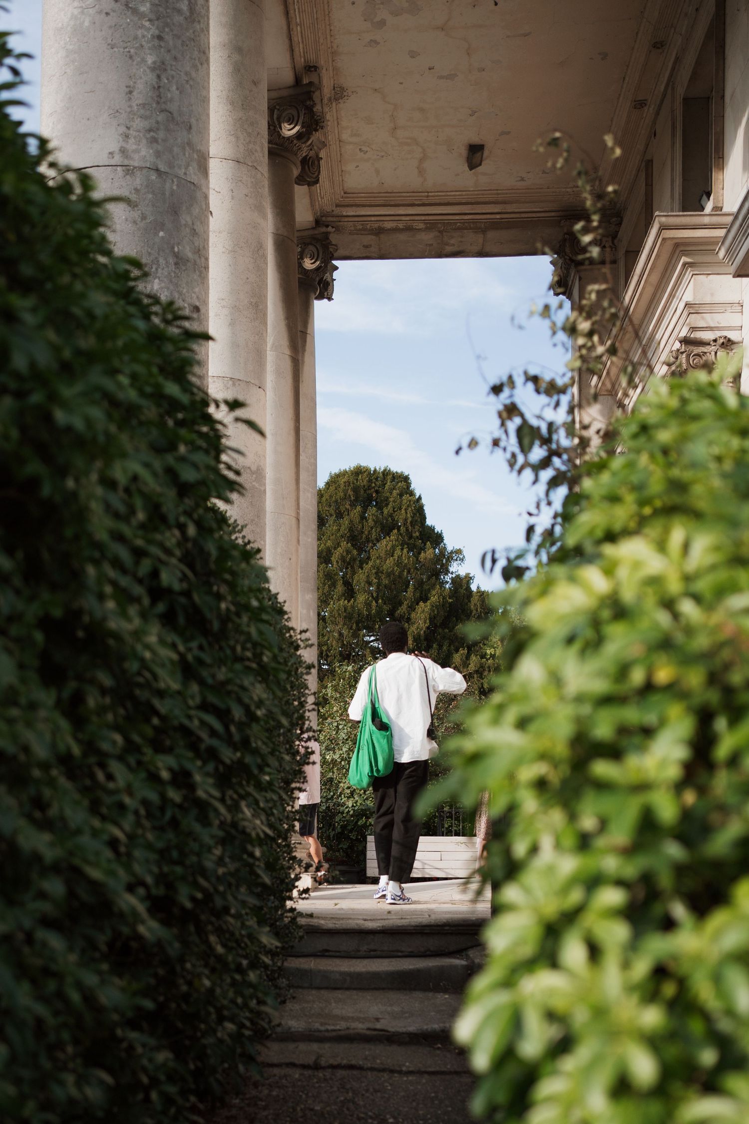 Architectural walkway with columns and greenery creating a dramatic perspective view.