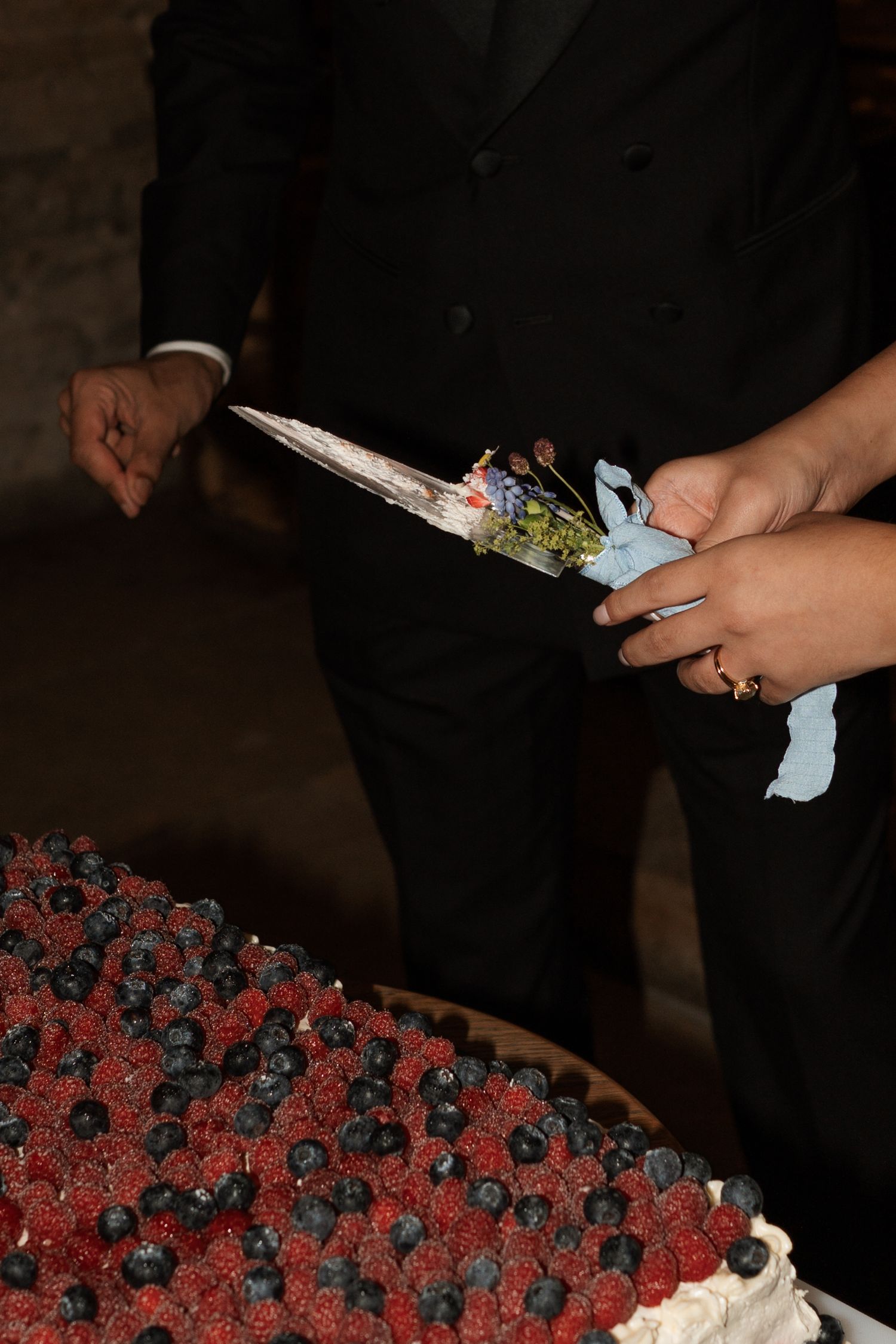 Close-up of hands cutting into a decorative cake with red and black details.