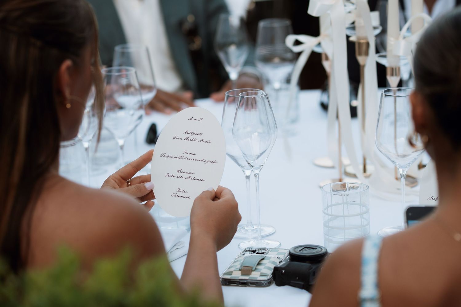 Elegant table settings at an outdoor wedding reception with wine glasses and place cards.