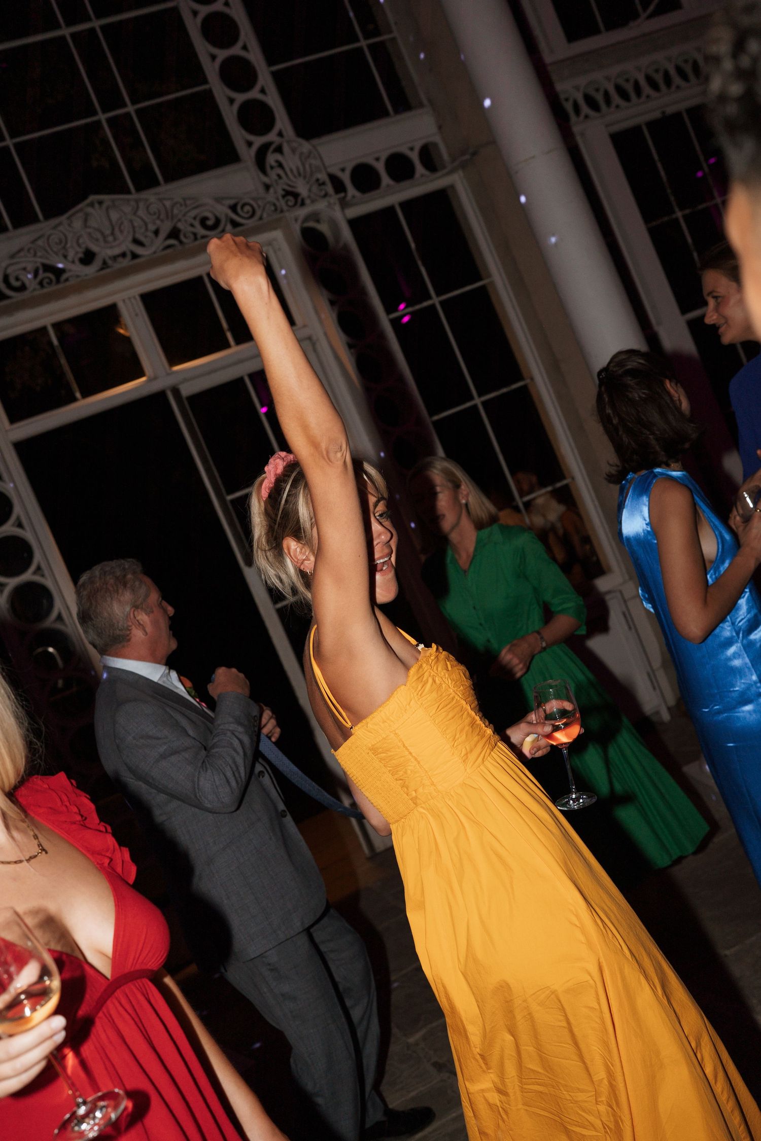 Wedding reception dance floor with guests dancing in colorful formal attire.