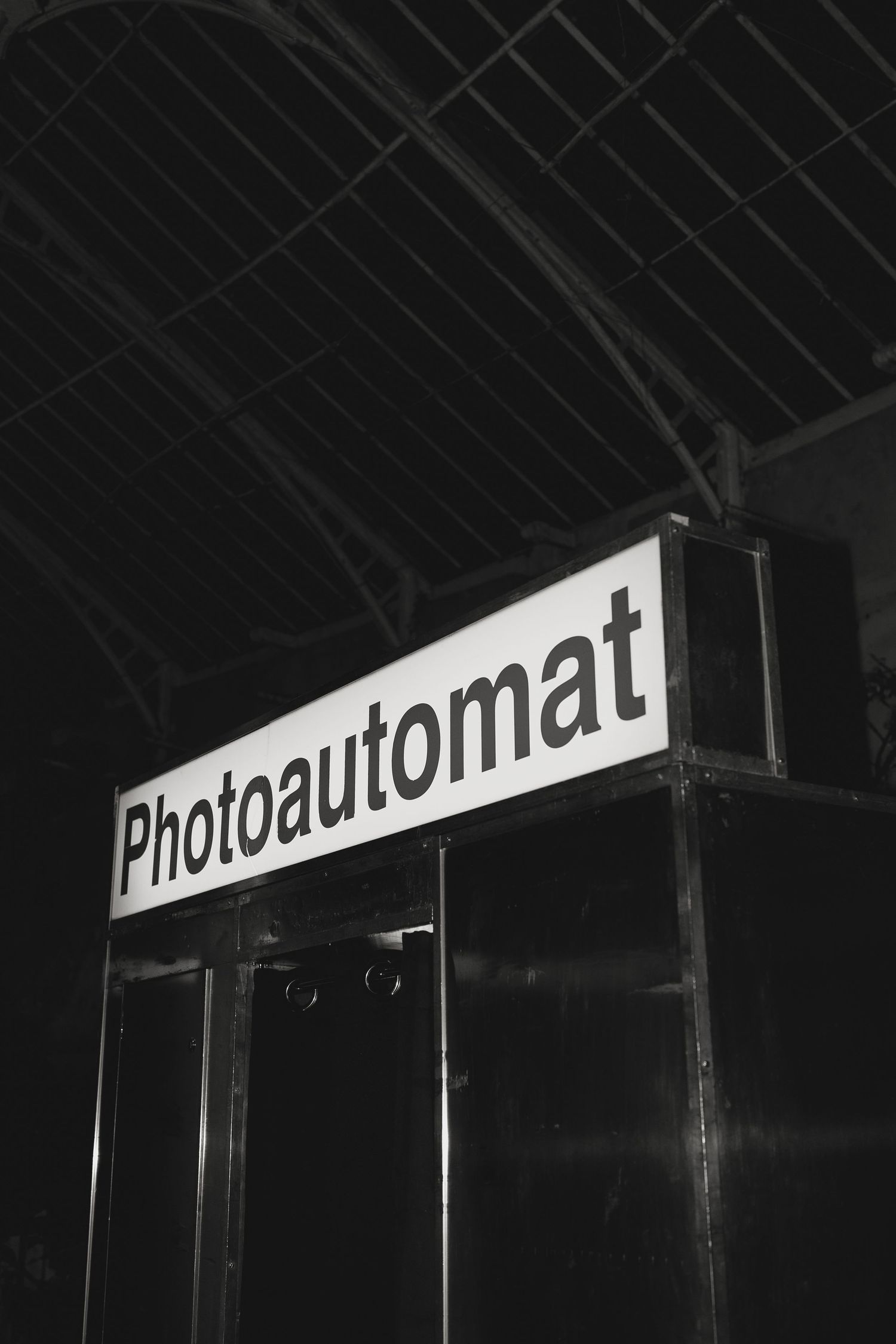 Black and white sign reading 'Photoautomat' illuminated at night.