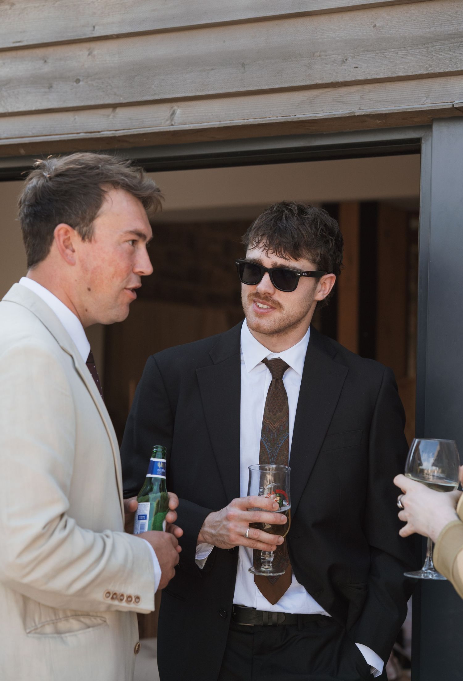 Two people in formal attire having drinks and conversation at an indoor event.