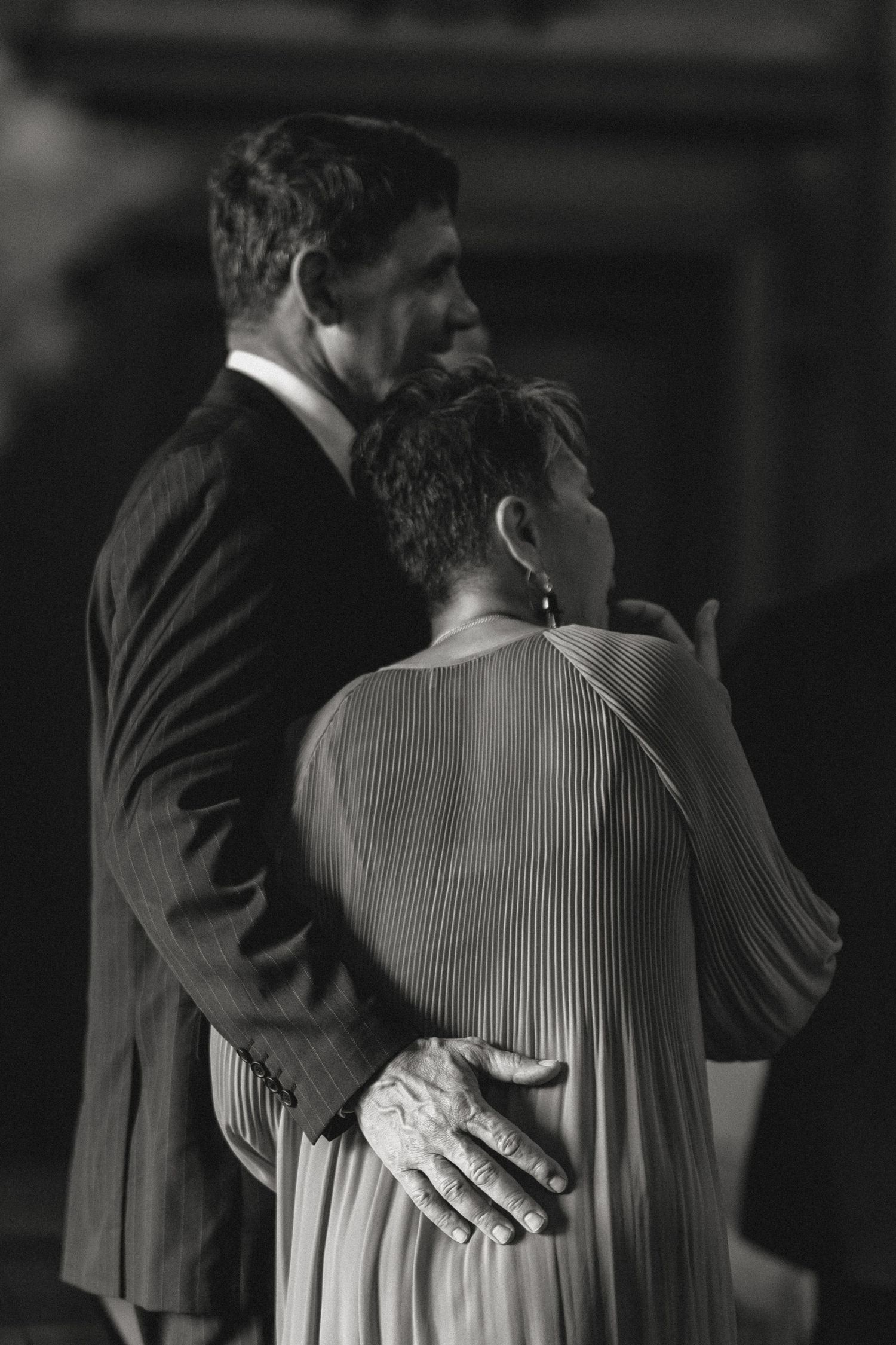 A couple embracing in formal attire captured in dramatic black and white photography.