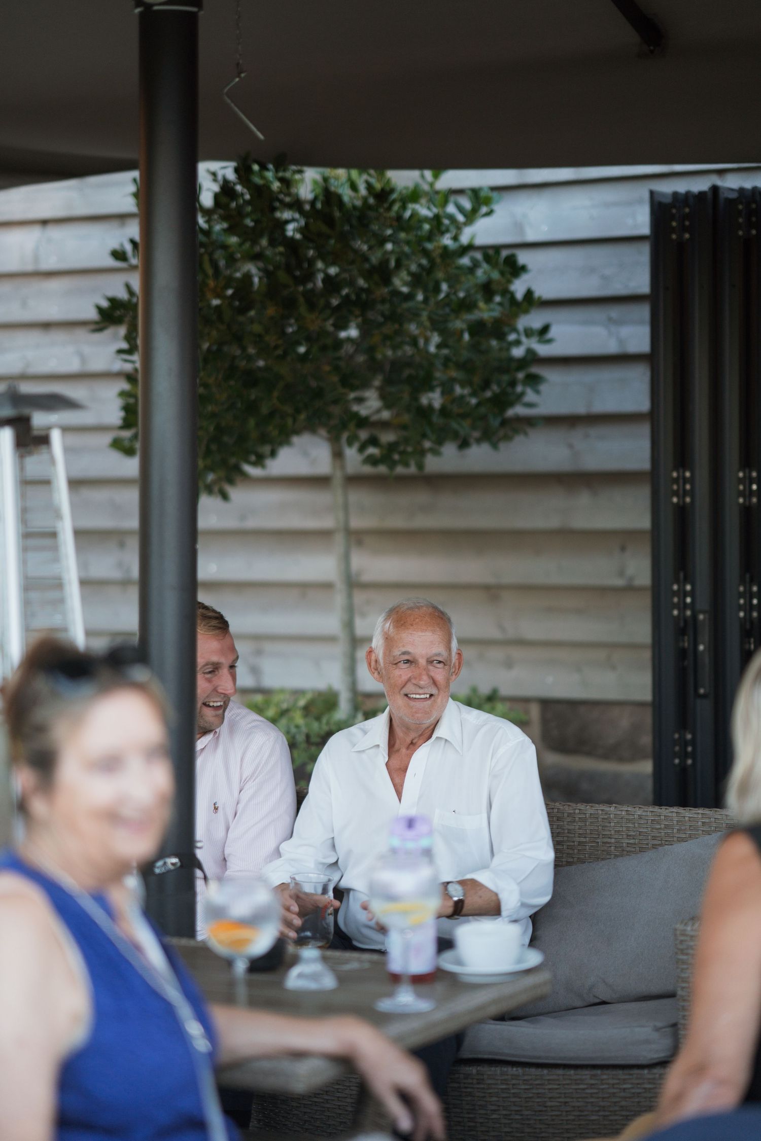 People relaxing on outdoor patio furniture during a social gathering.