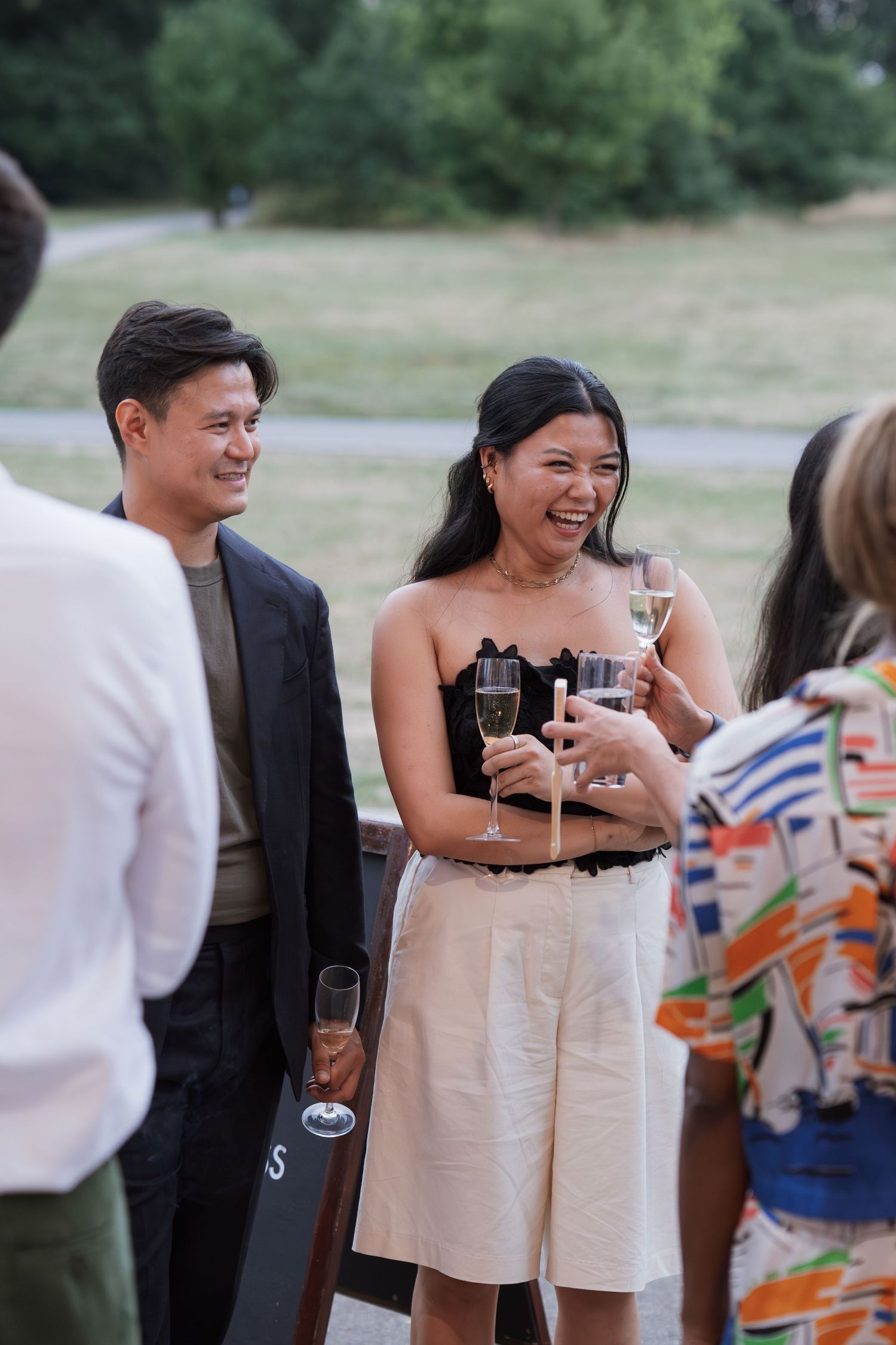 Wedding guests in formal attire enjoying champagne at an outdoor celebration.
