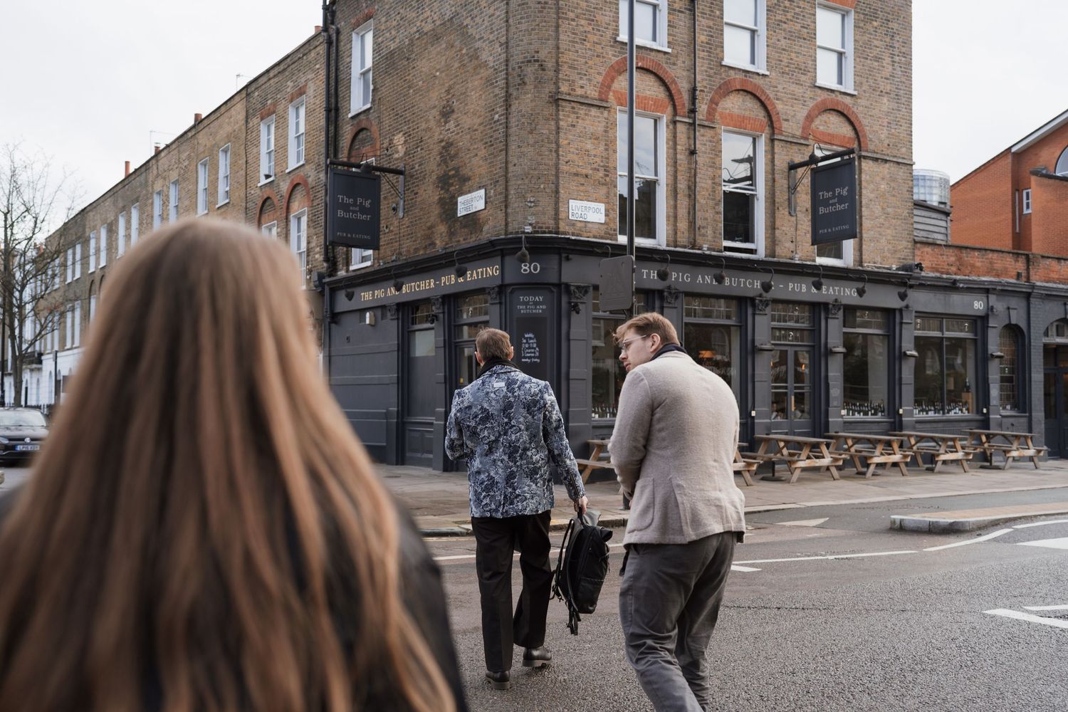 A crowd of people gathered outside a brick building on a city street.