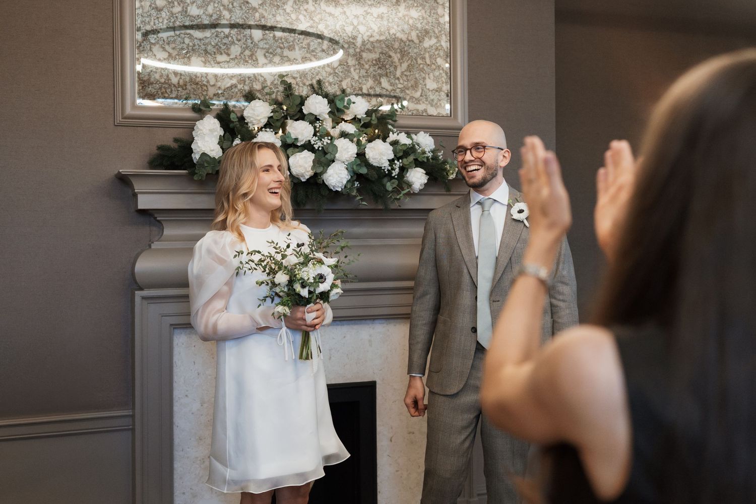 A wedding ceremony moment captured with white floral arrangements in the background.