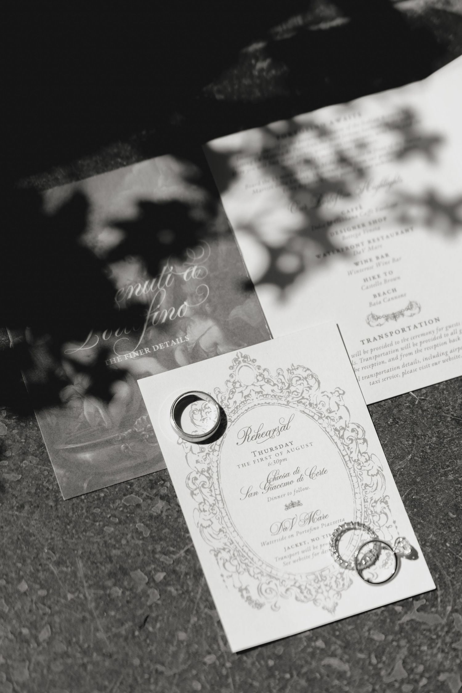 Elegant wedding invitations with ornate decorative borders laid out on a dark surface.