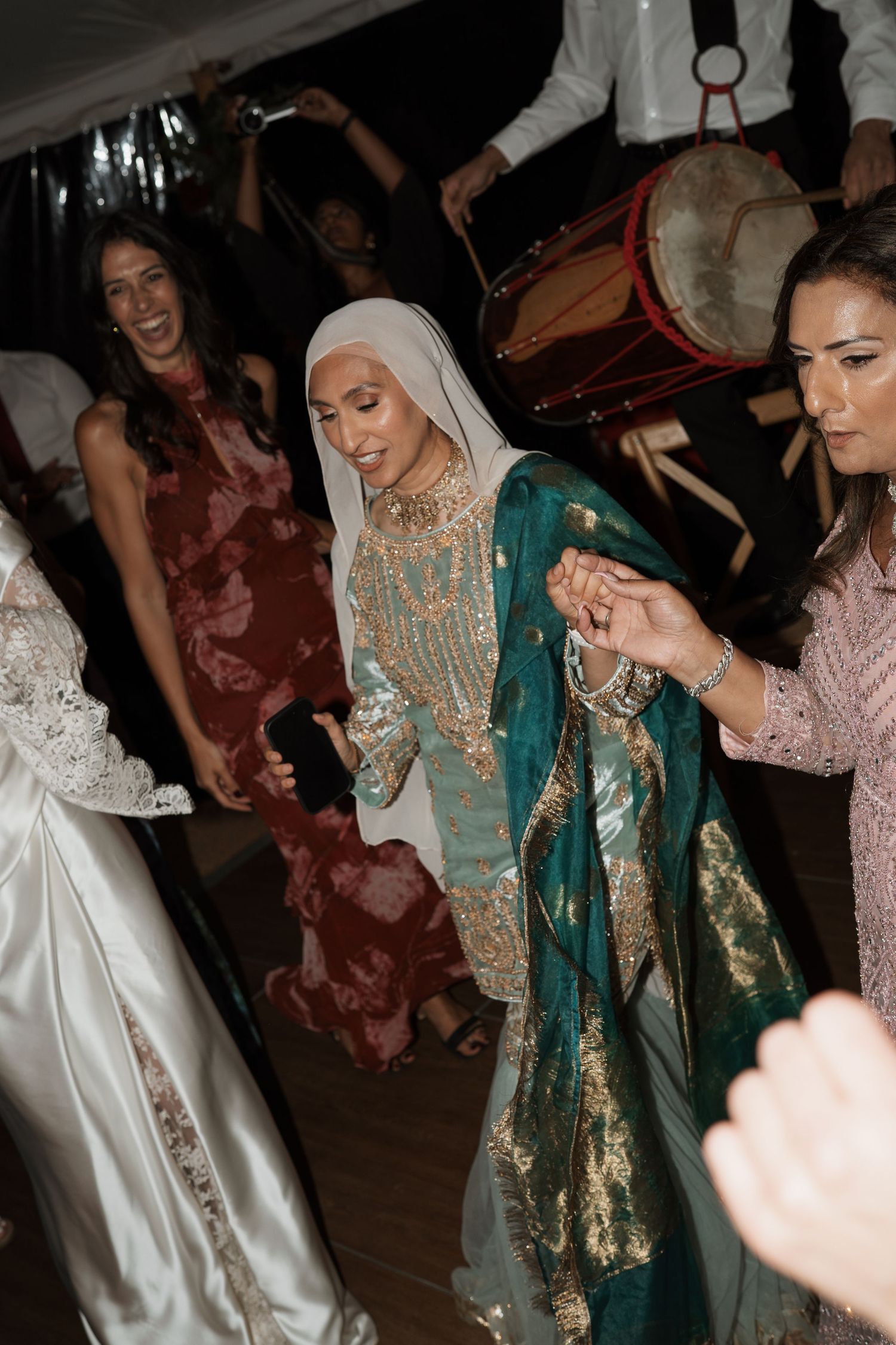 Wedding guests dancing and celebrating in traditional cultural attire at a reception party.