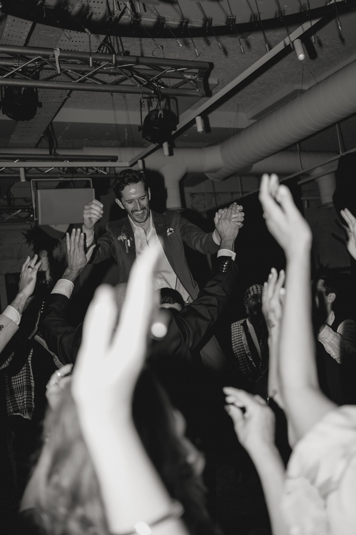 Black and white photo of an energetic crowd with raised hands at a celebration.