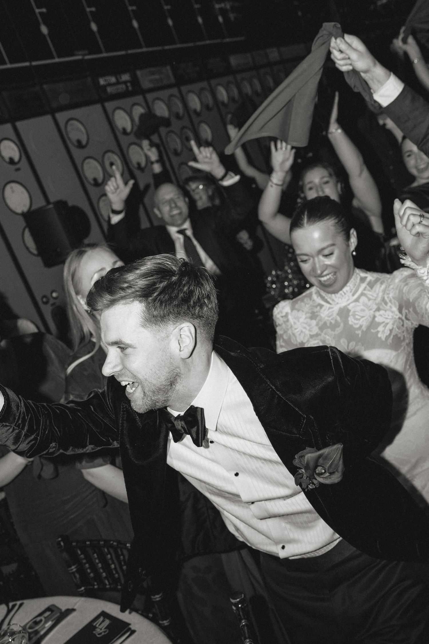 Black and white photo showing joyful dancing and celebration at formal event.