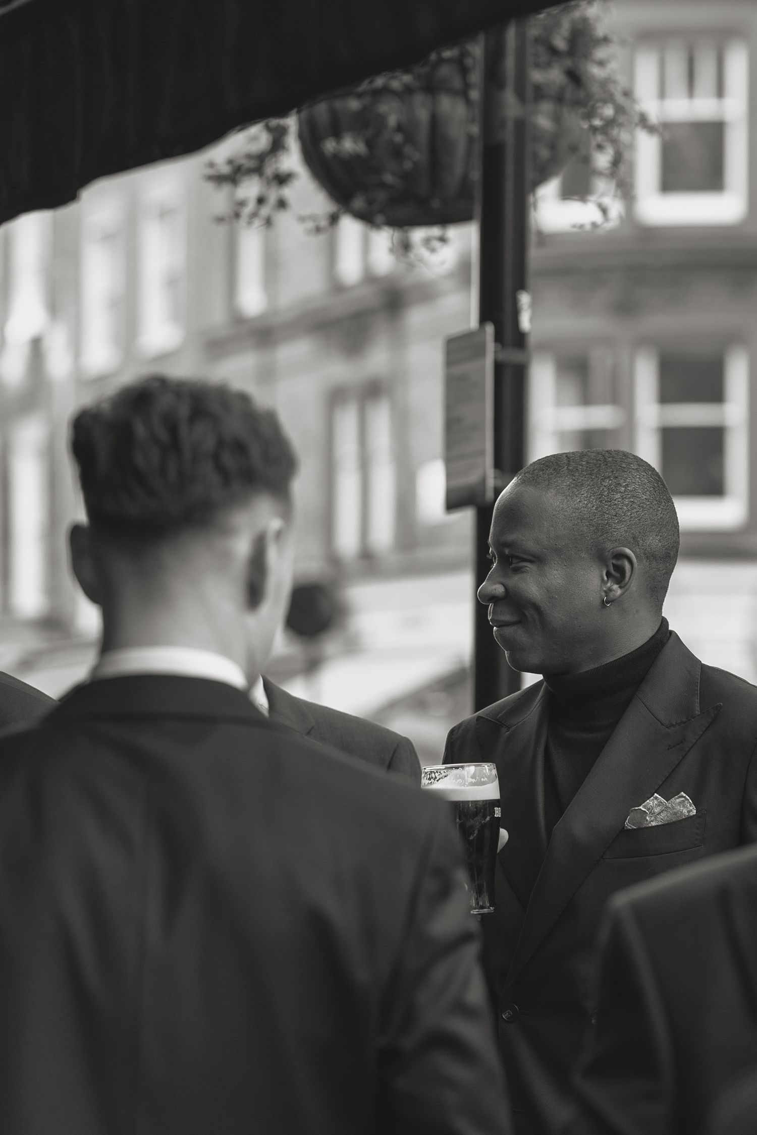 Guests in formal black tie attire mingling outside an establishment.