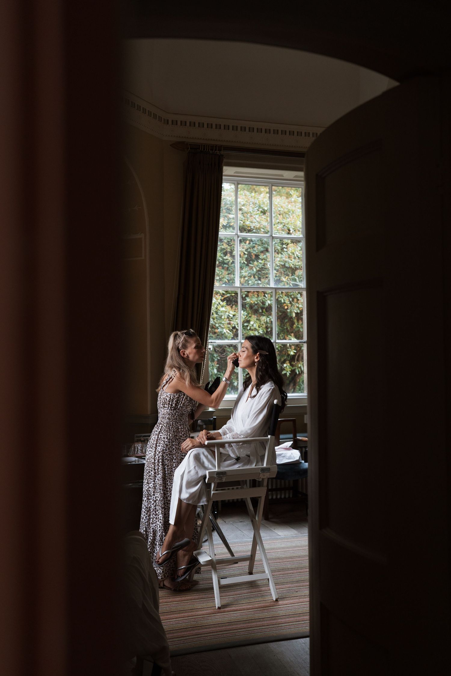 Silhouette of someone getting ready in a sunlit room with large windows.