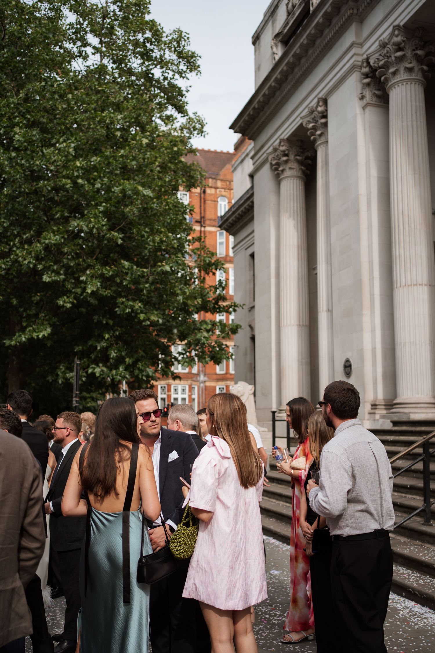 Wedding guests mingling outside a building with classical columns.