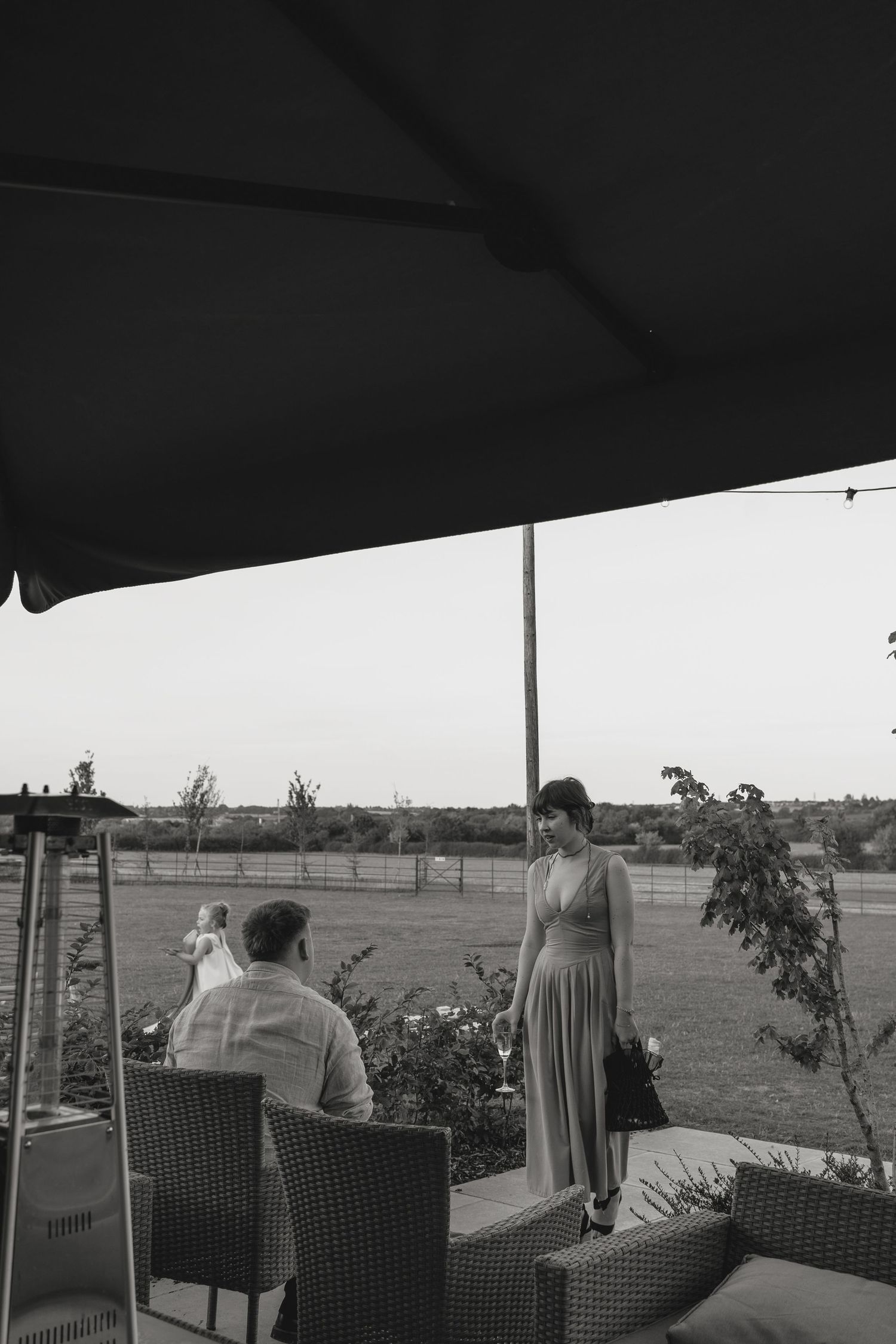 Black and white photo of an outdoor patio setting with seating under an umbrella.