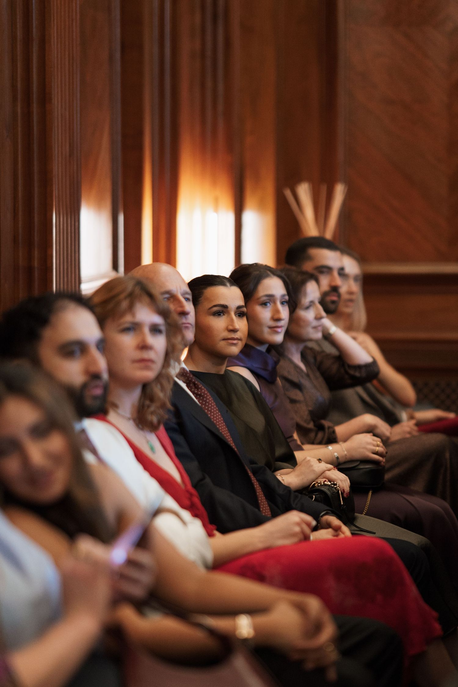 An audience seated in red theater chairs watching a presentation.