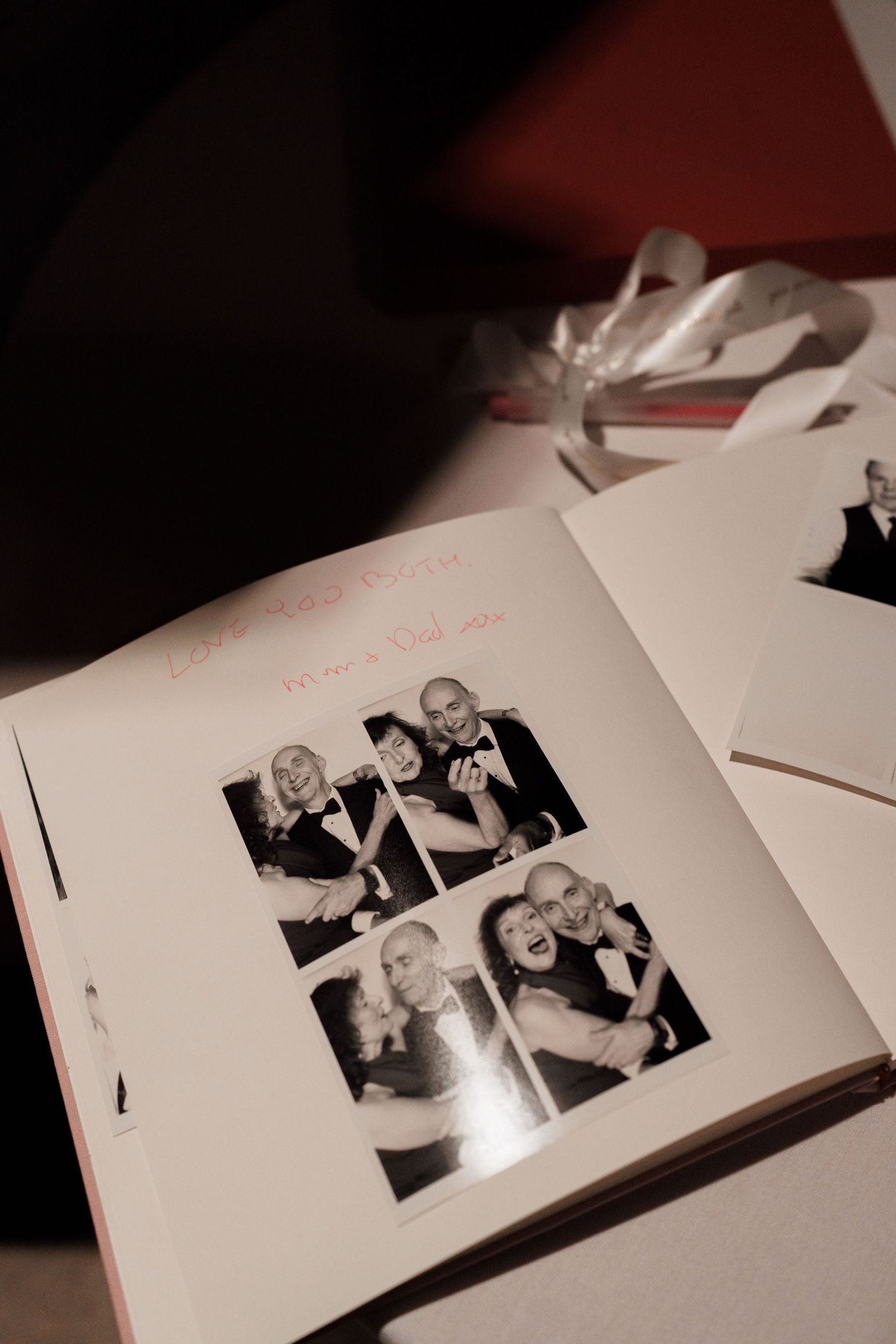Wedding photo album pages spread open on a dark surface showing black and white photographs.
