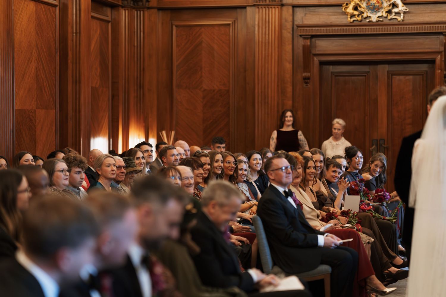 Elegant wood-paneled reception hall filled with wedding guests during ceremony.