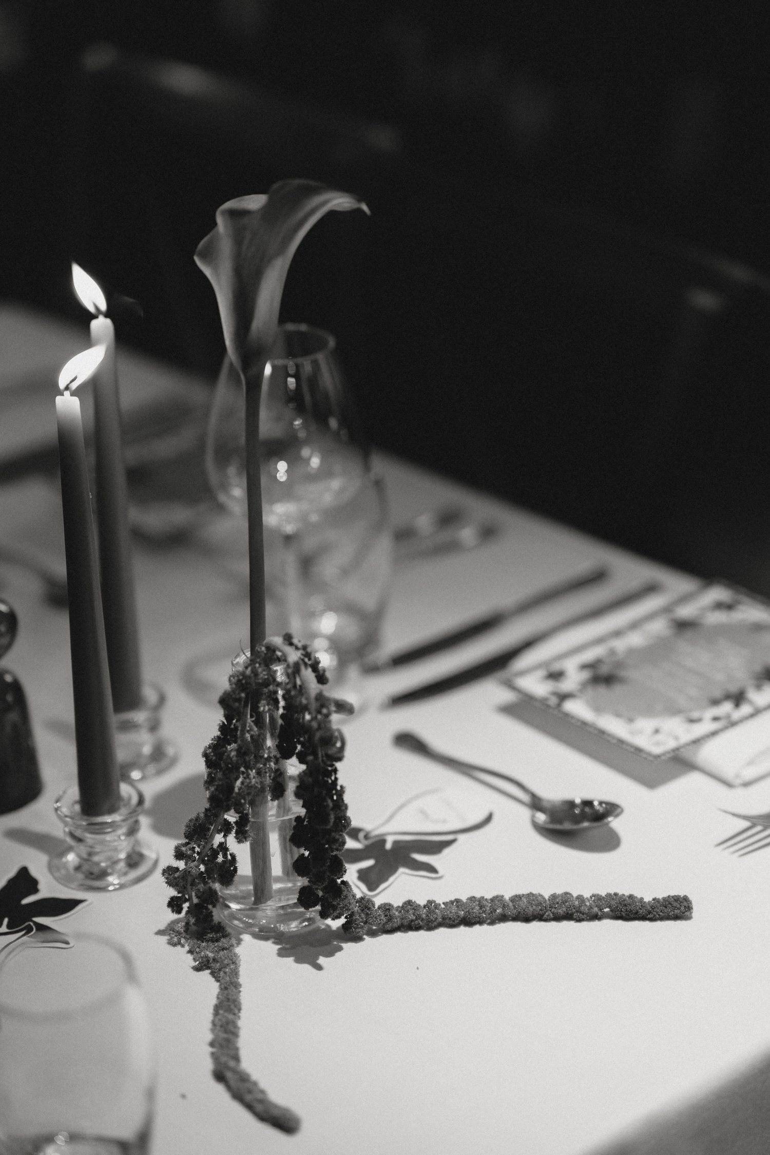 Black and white detail of candles and table decorations at a formal dinner.