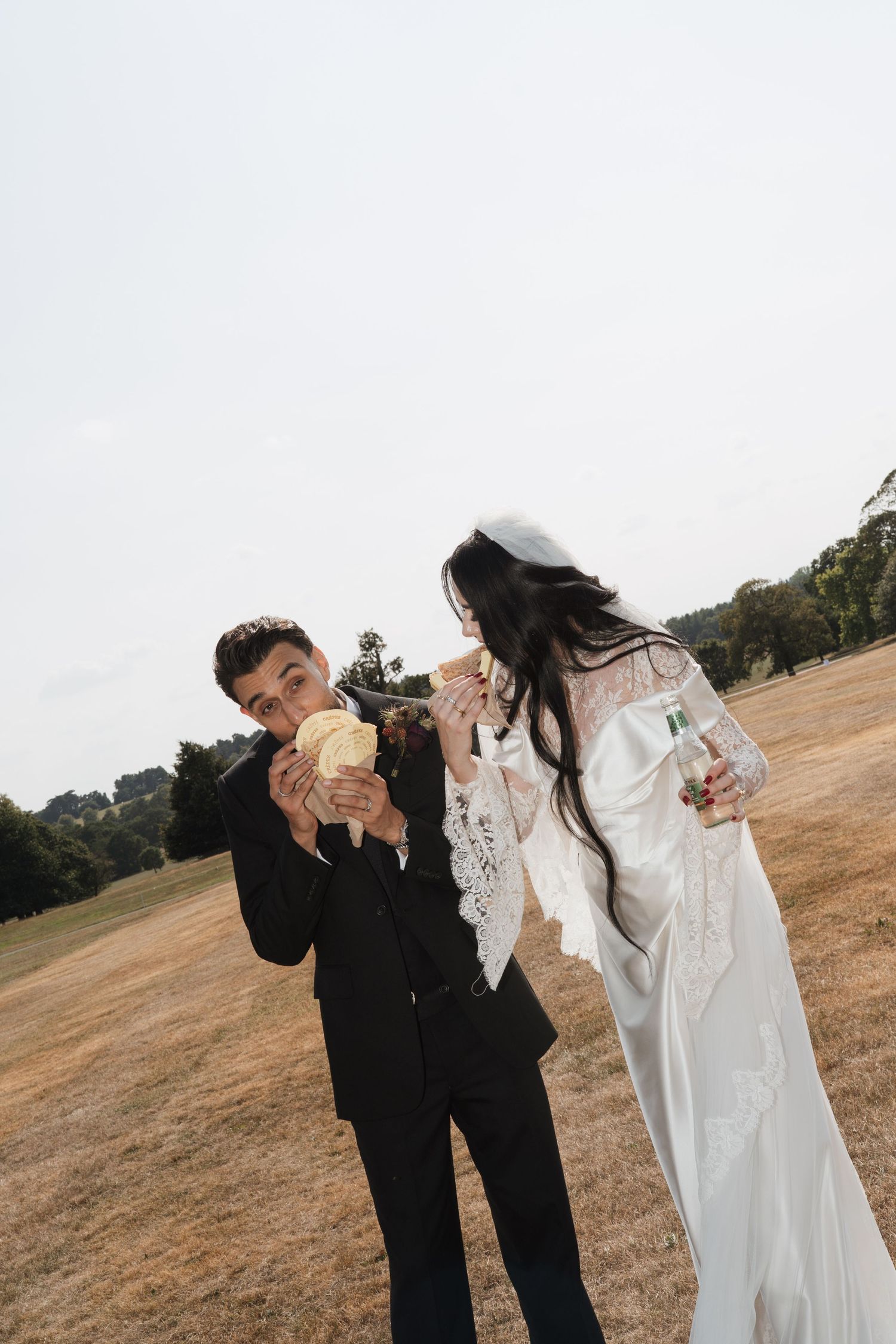 Wedding party members sharing candid laughing moments in a sunlit field.