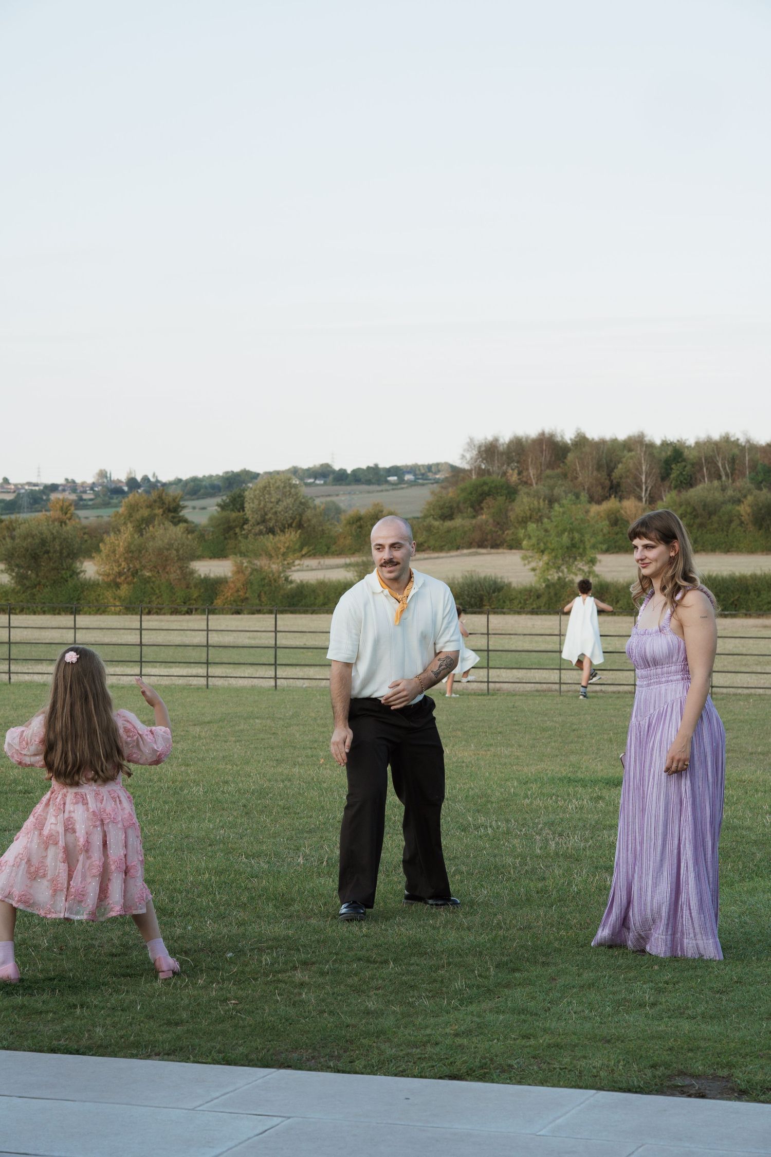 Outdoor wedding scene with guests in formal attire enjoying festivities on a lawn.
