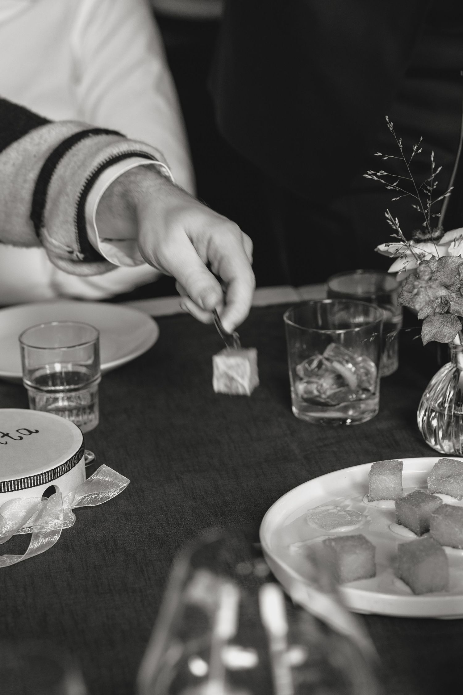 Black and white close-up of place settings and glassware at a formal dining table.