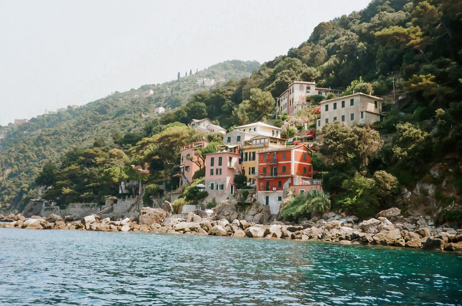 Scenic coastal view of colorful Italian villas nestled along rocky Mediterranean cliffs.