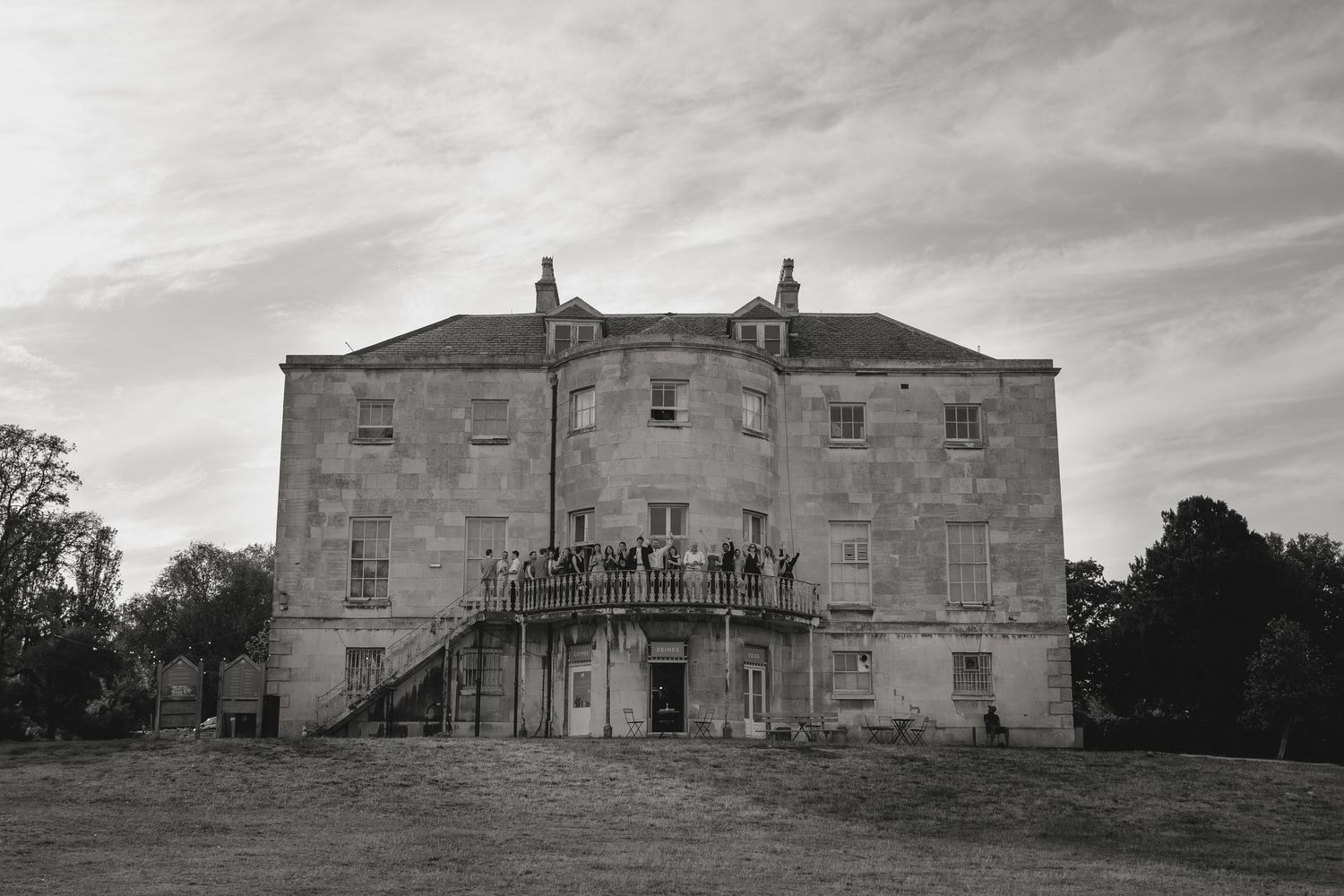 Panoramic view of a grand historic mansion under dramatic cloudy skies.