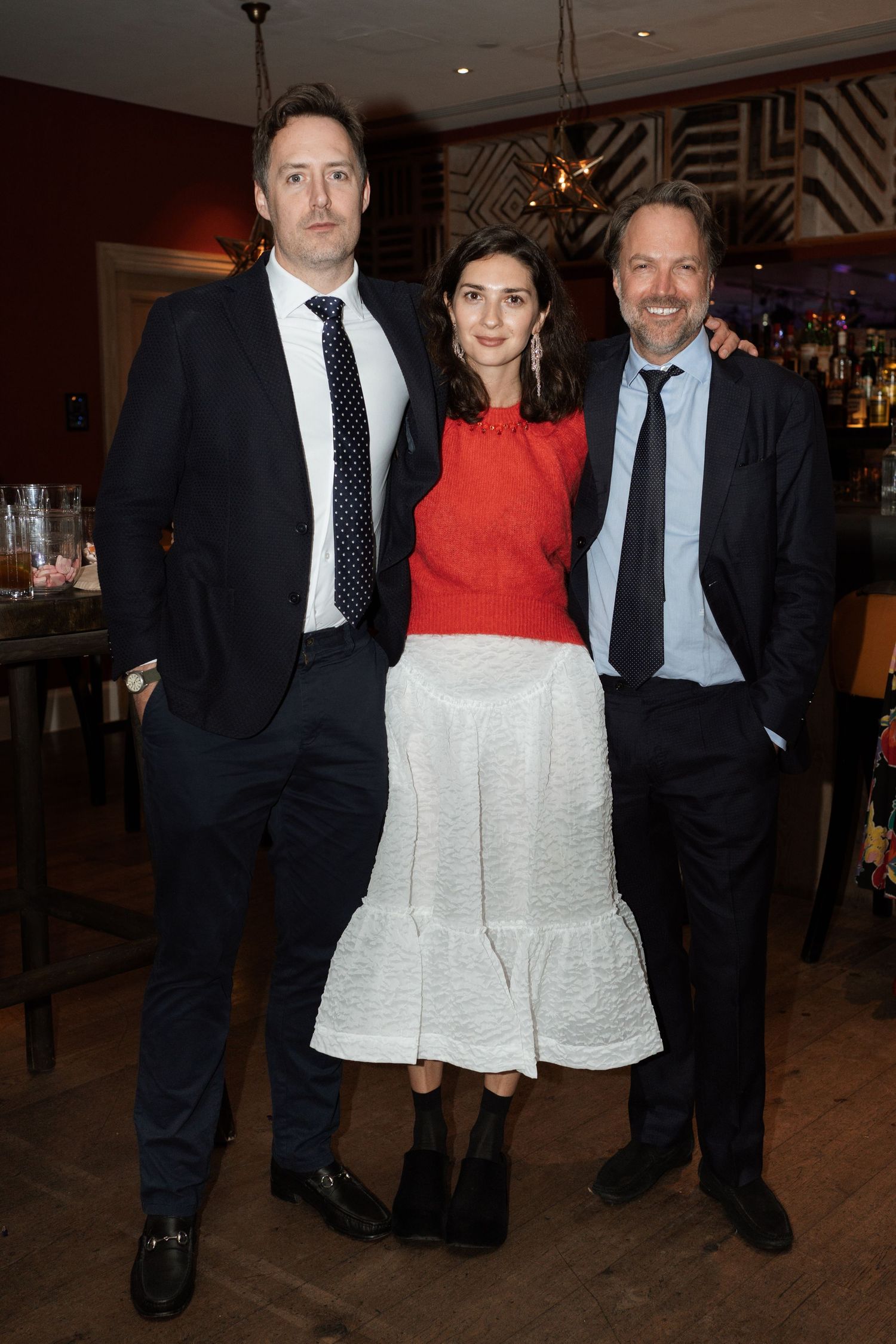Three people posing together at a formal event in elegant attire.